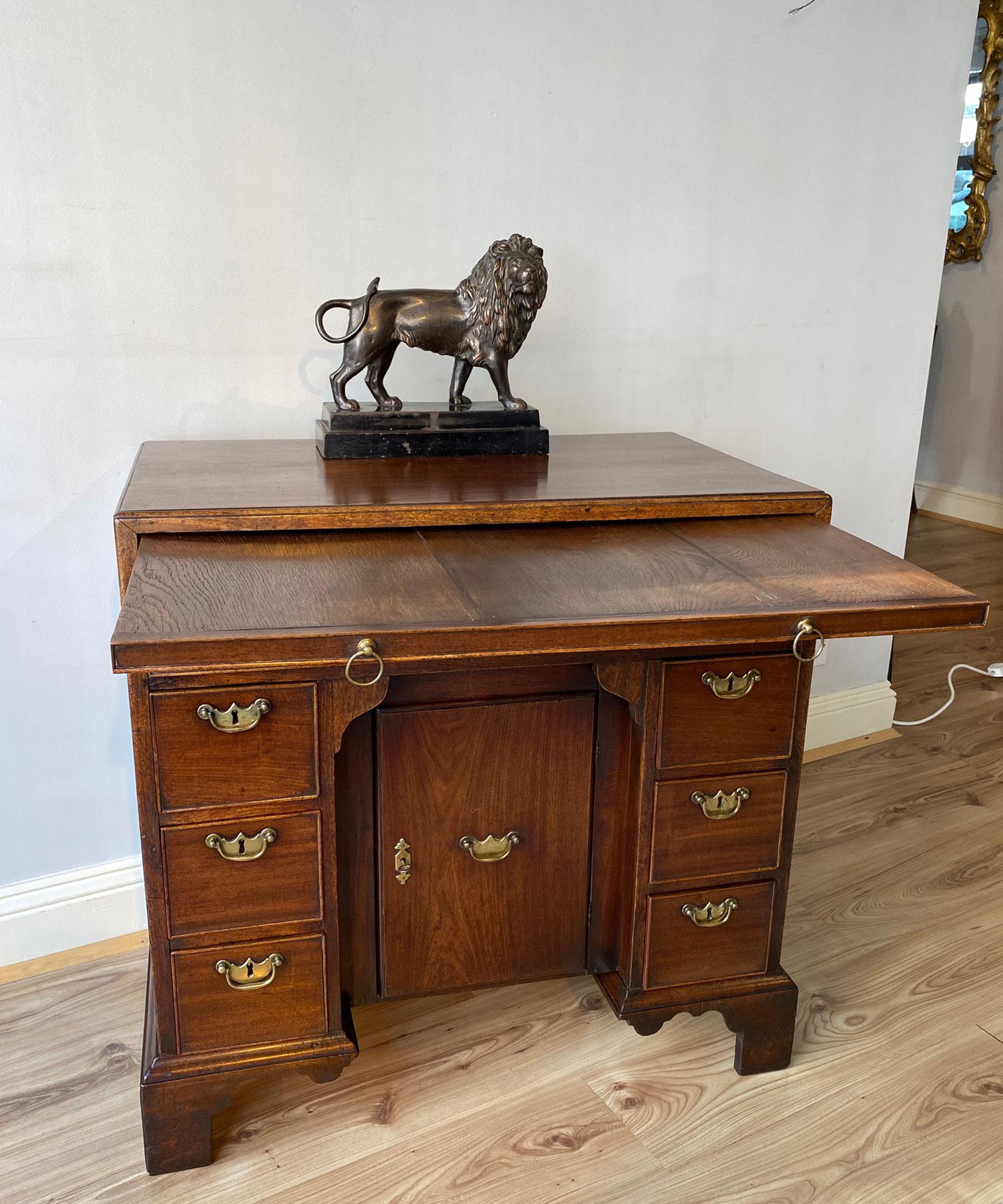 A fine George II mahogany kneehole desk with cabinet-maker or retailer's label for Lowdell, Southwark. The desk's caddy moulded top above a brushing slide and a long drawer; having a central pull-forward door flanked by banks of three graduated