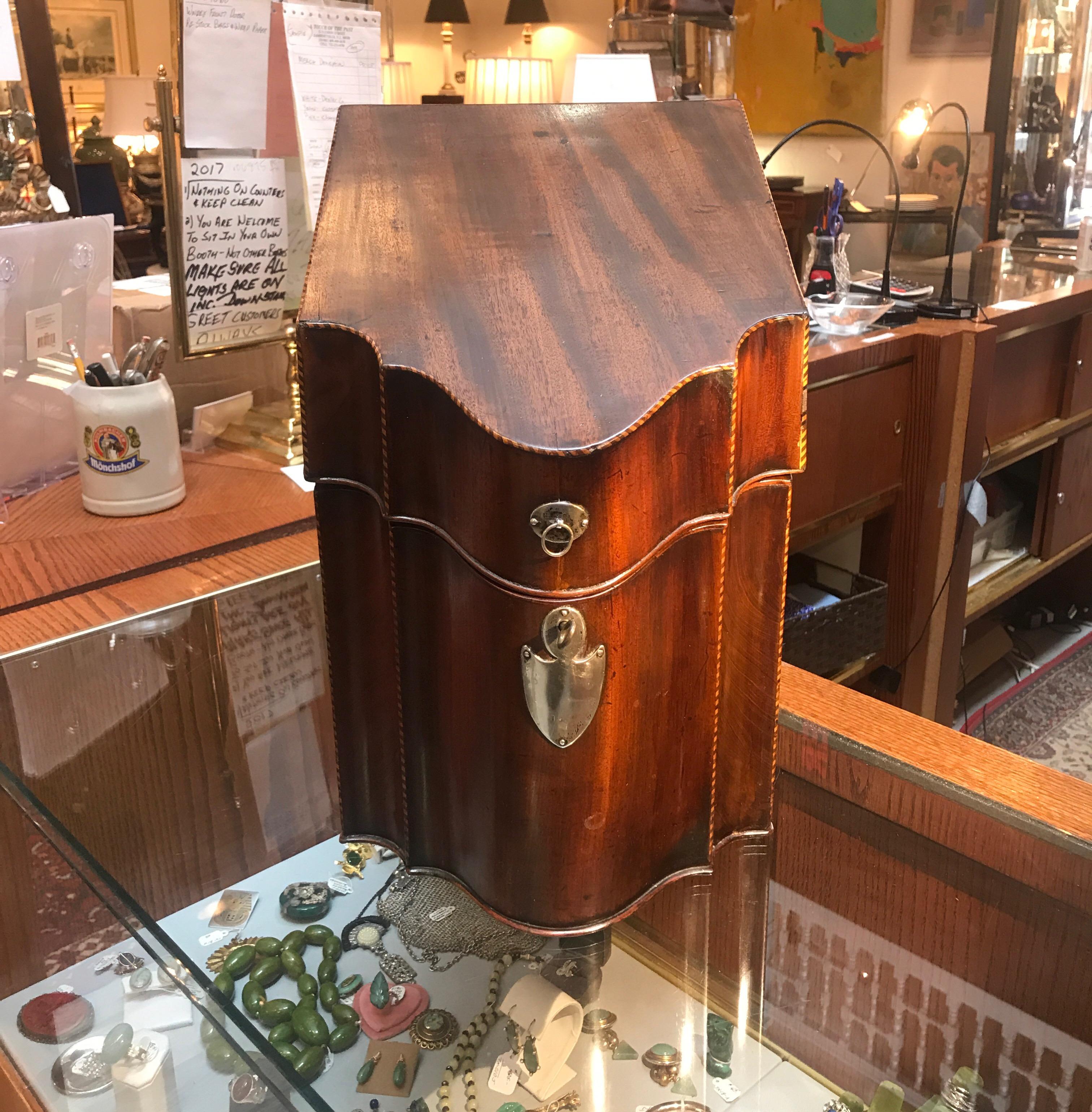 Elegant and early Georgian mahogany knife box with sterling mounts. The shapely scalloped front with silver shield escushion and handle with replaced key. The interior has had the knife fittings removed for functioning large and open storage, often