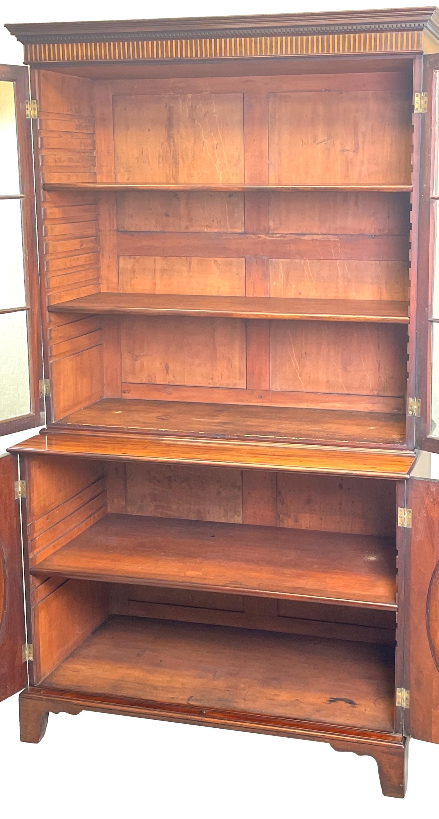 A superb quality 18th century Georgian mahogany library bookcase of relatively small proportions having inlaid cornice and two astragal glazed doors enclosing adjustable shelves to top over wonderfully figured pair of oval panelled cupboard doors