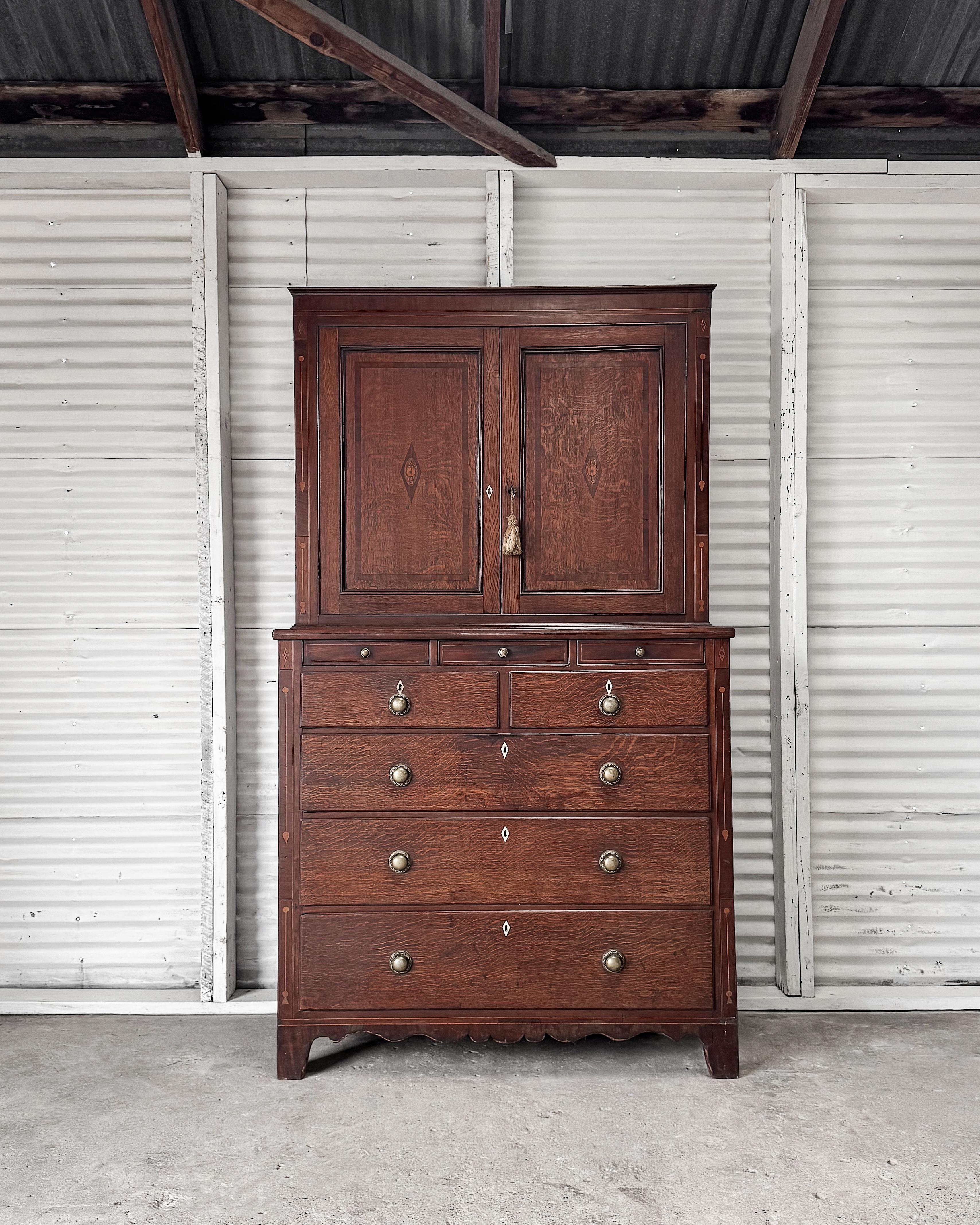 This Georgian period linen press showcases a balance of practicality and refined craftsmanship, embodying the neoclassical style with clean lines and understated sophistication. Constructed from rich mahogany, the two-part piece features decorative