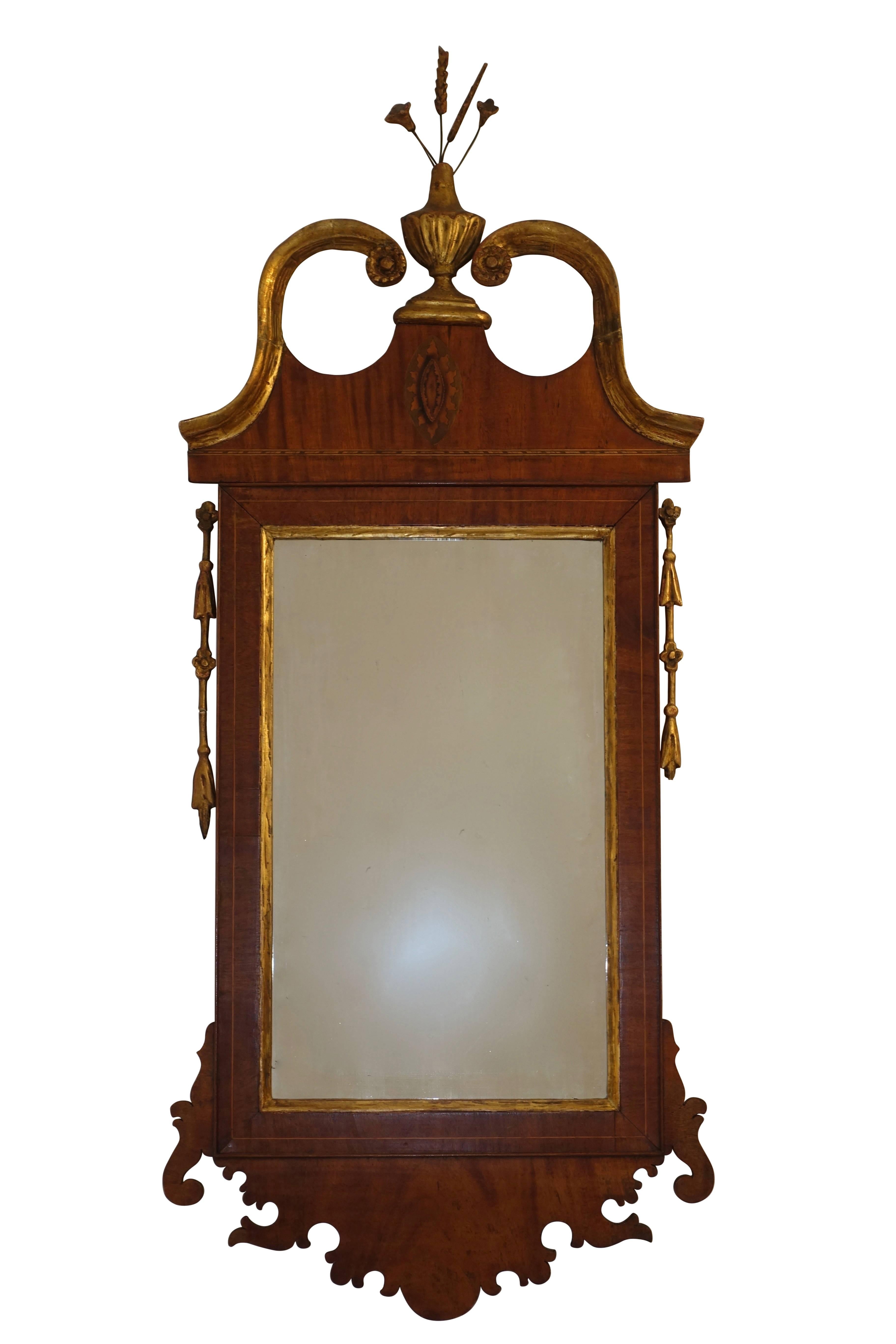 Georgian period mahogany framed mirror with satinwood inlay, having a gilt broken arch pediment centering an urn with floral spray, England, 19th century.