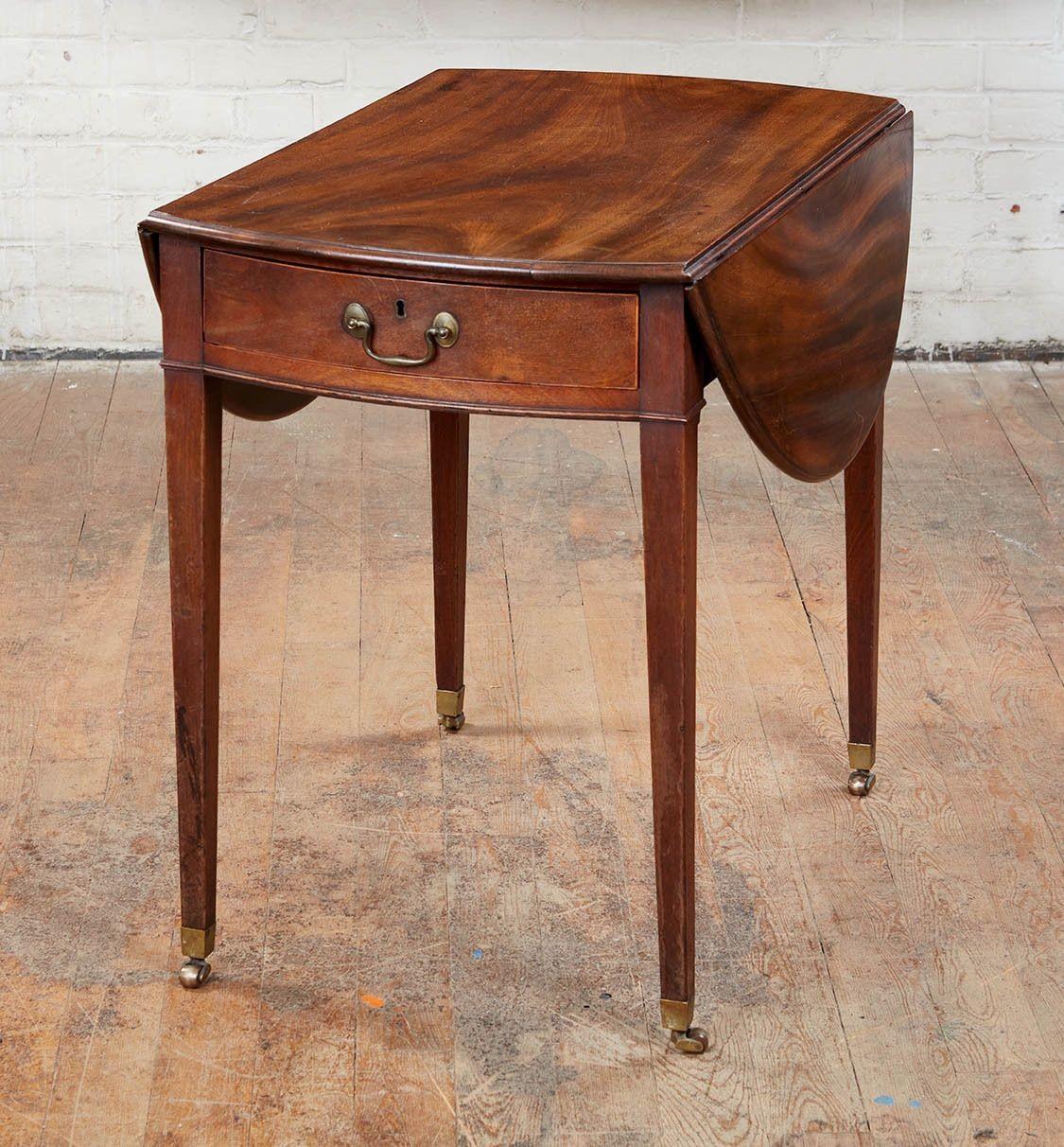 Fine George III mahogany Pembroke table, the vividly grained oval top with molded edge, over single shaped drawer retaining original hardware and standing on square tapered legs ending in original brass box casters, the whole possessing good rich