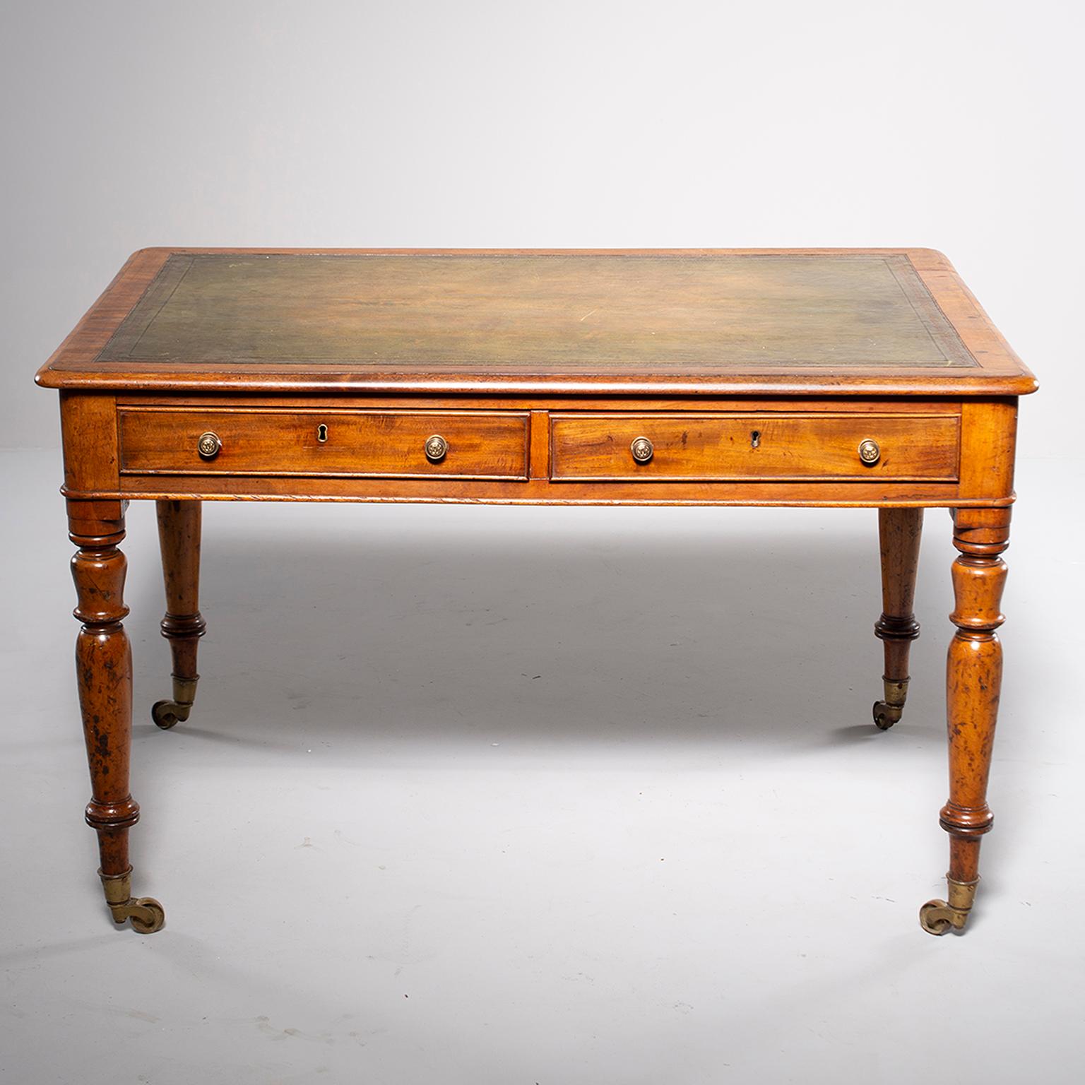 Georgian partner’s desk is made of mahogany with turned legs on casters, two functional drawers on both sides and a new green leather top with embossed edges, circa 1870s. Overall excellent antique condition.