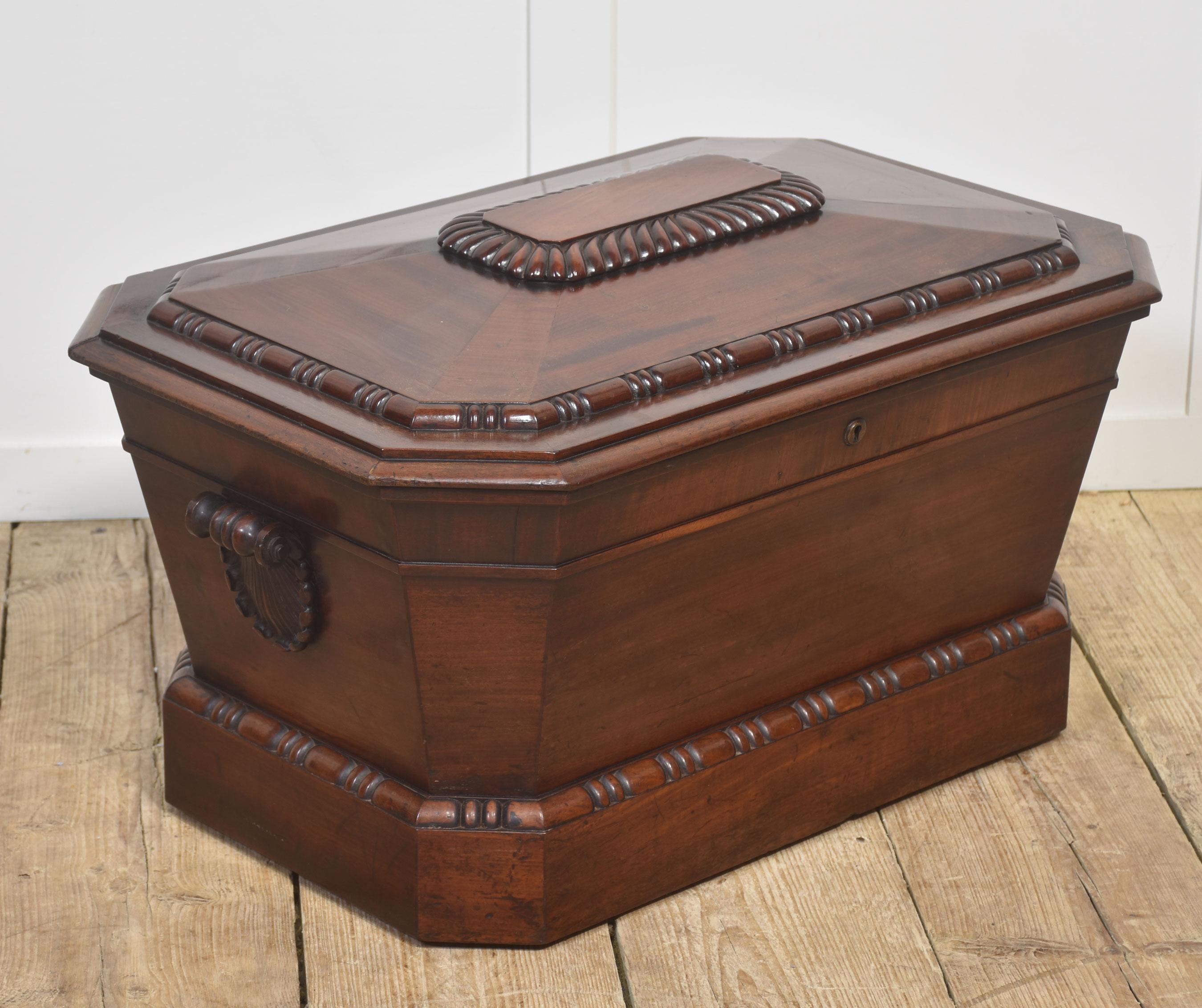 This impressive early 19th-century mahogany cellarette is crafted in the refined sarcophagus form associated with the late Georgian and Regency periods. Fashioned from richly figured mahogany, it features a beautifully faceted lid with a raised