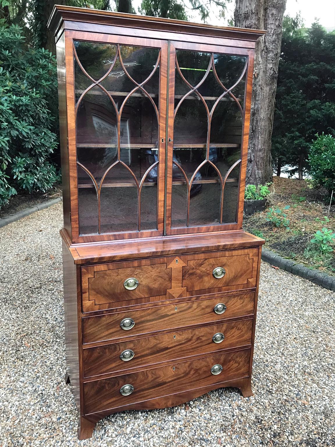 A high quality Georgian mahogany secretaire bookcase chest of drawers with two glazed doors over base with original sliding shelves, pull out secretaire drawer enclosing pigeon holes and drawers, over three long graduated drawers with brass handles