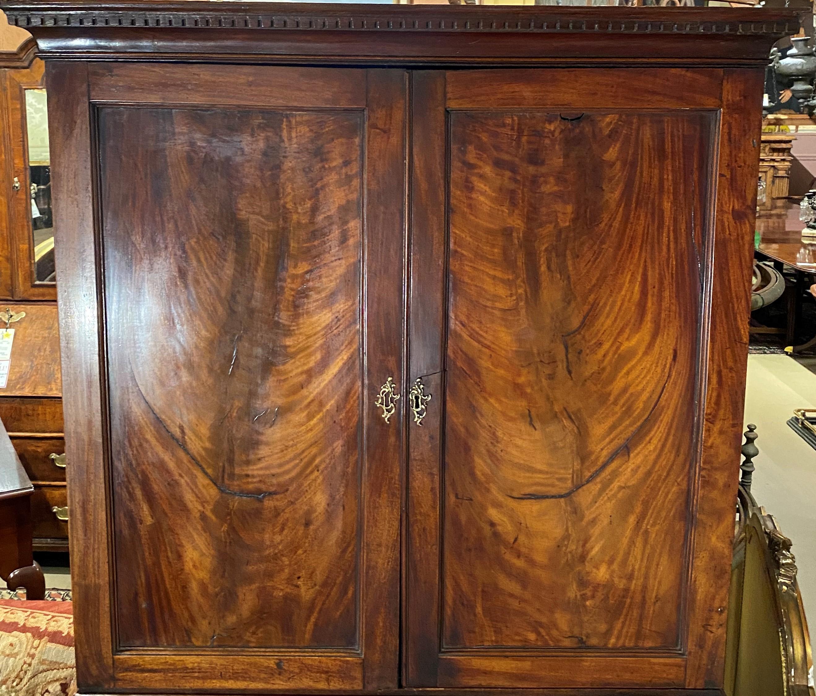 A fine Georgian two part mahogany secretary bookcase, its upper case with a molded cornice surmounting two blind paneled doors with crotched mahogany veneer, opening to adjustable book cubbies and storage, over a lower case with slant top, opening