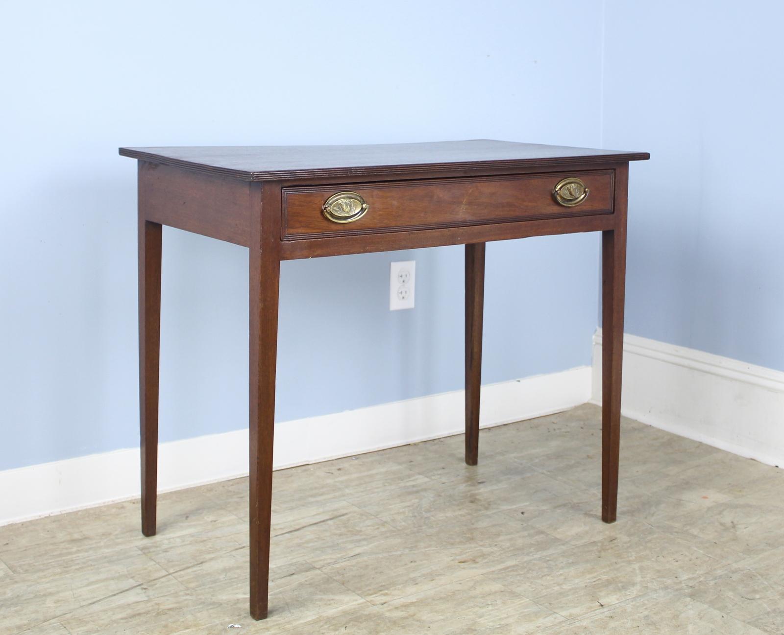 An antique occasional table from England. Classic Georgian shape. Mahogany with a rich grain and patina. One wide drawer with classic brass handles under reeded edge. Would make a suitable lamp table. Top has been lightly refinished.