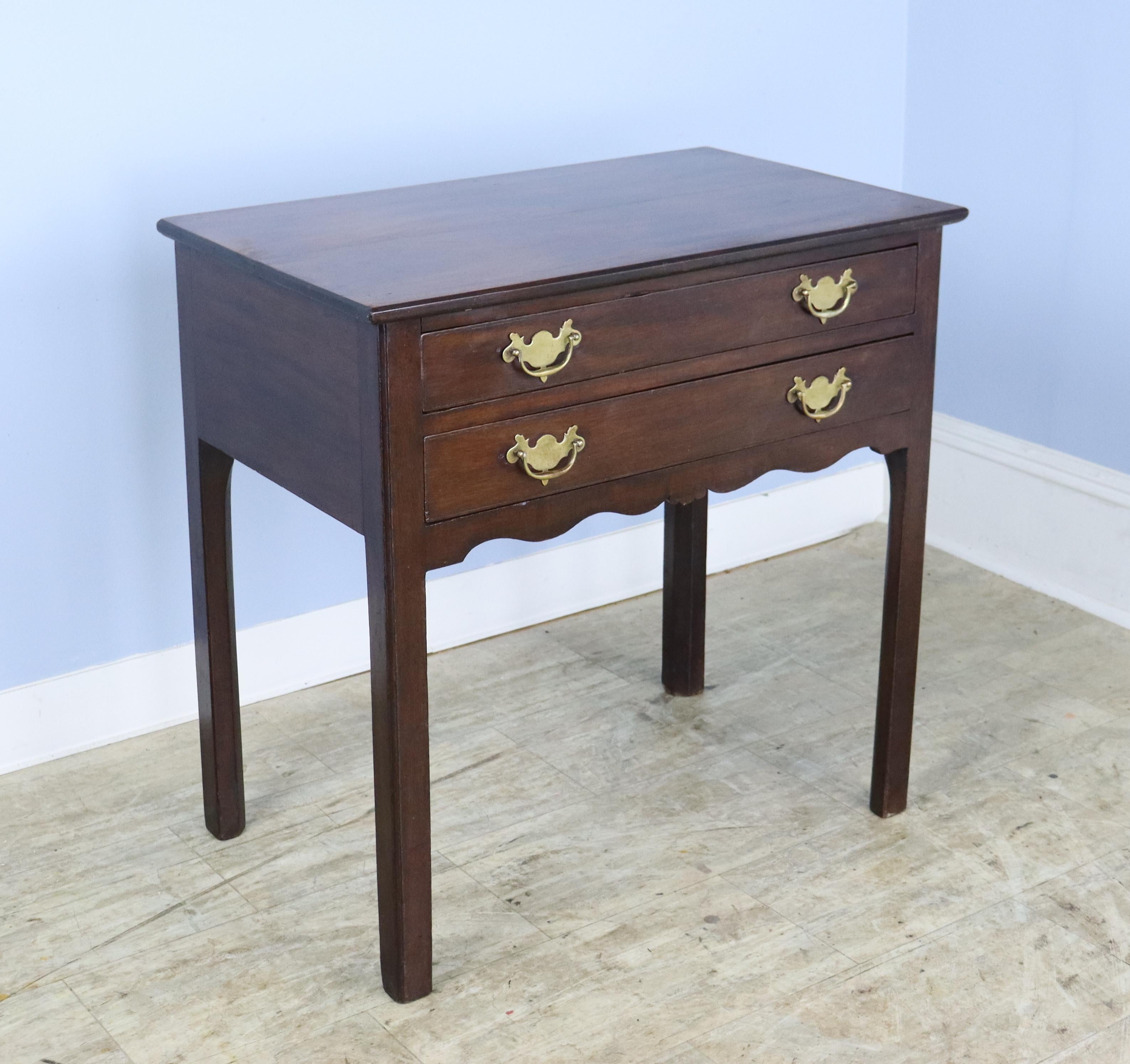 A handsome two drawer Georgian side table, quite sturdy and the top is in very nice condition for its age.  The mahogany is well grained with little to no distress.  Solid straight legs are typical of the period.  The brasses appear to be original.