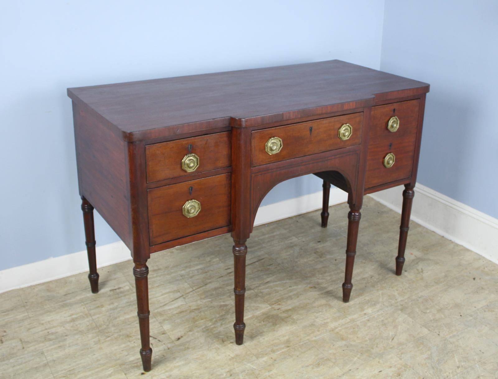 Quite formal and fabulous. This early mahogany sideboard has wonderful turned legs, good storage and a surprise double deep right drawer. Original ebony string inlay and good brass handles. Sturdy and stable. There is some age appropriate distress