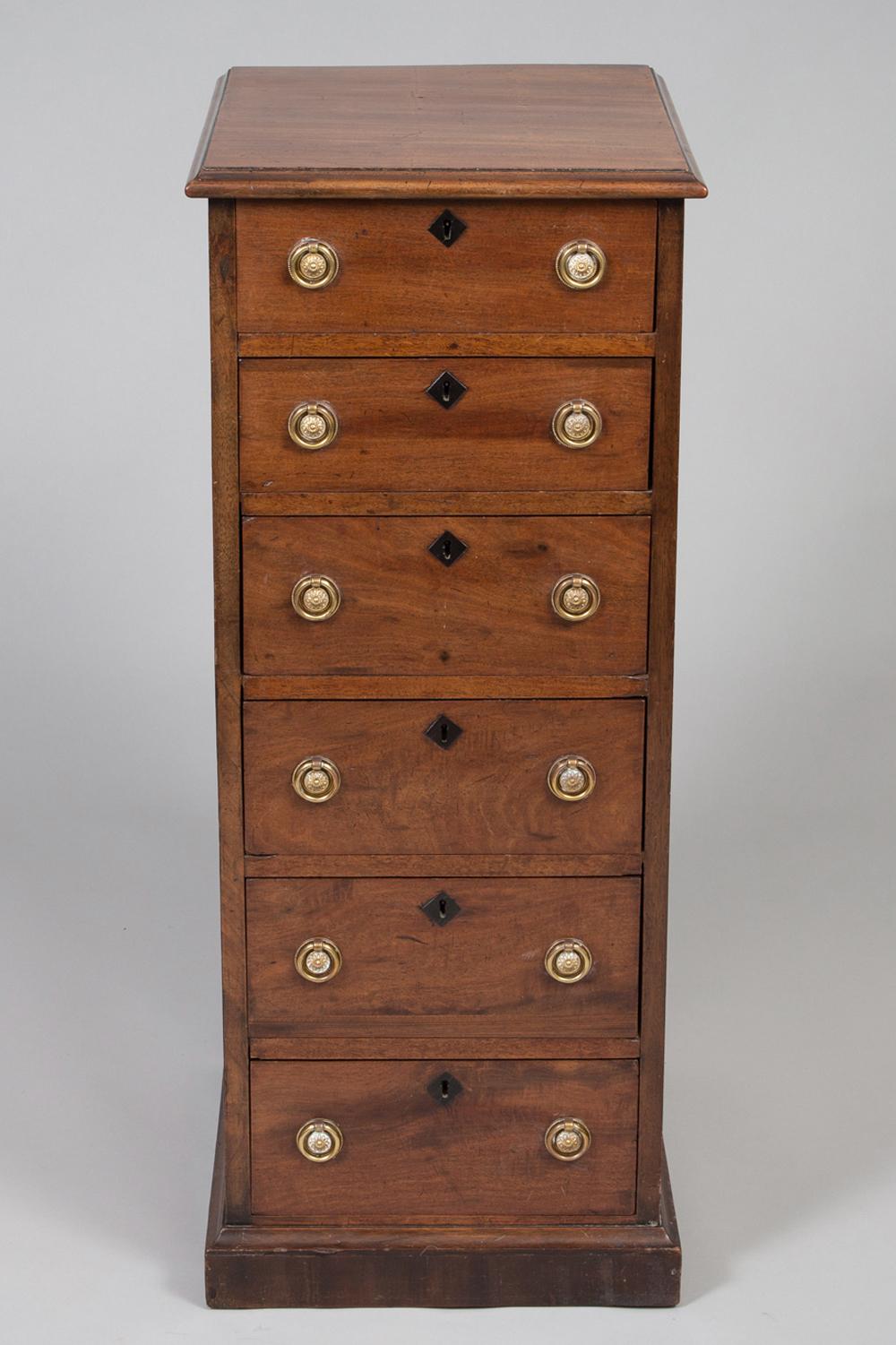 Late George III mahogany tall slender chest with six drawers, the rectangular top with molded edge, brass ring handles, diamond-shaped ebonized eschuteons, supported on a plinth base.