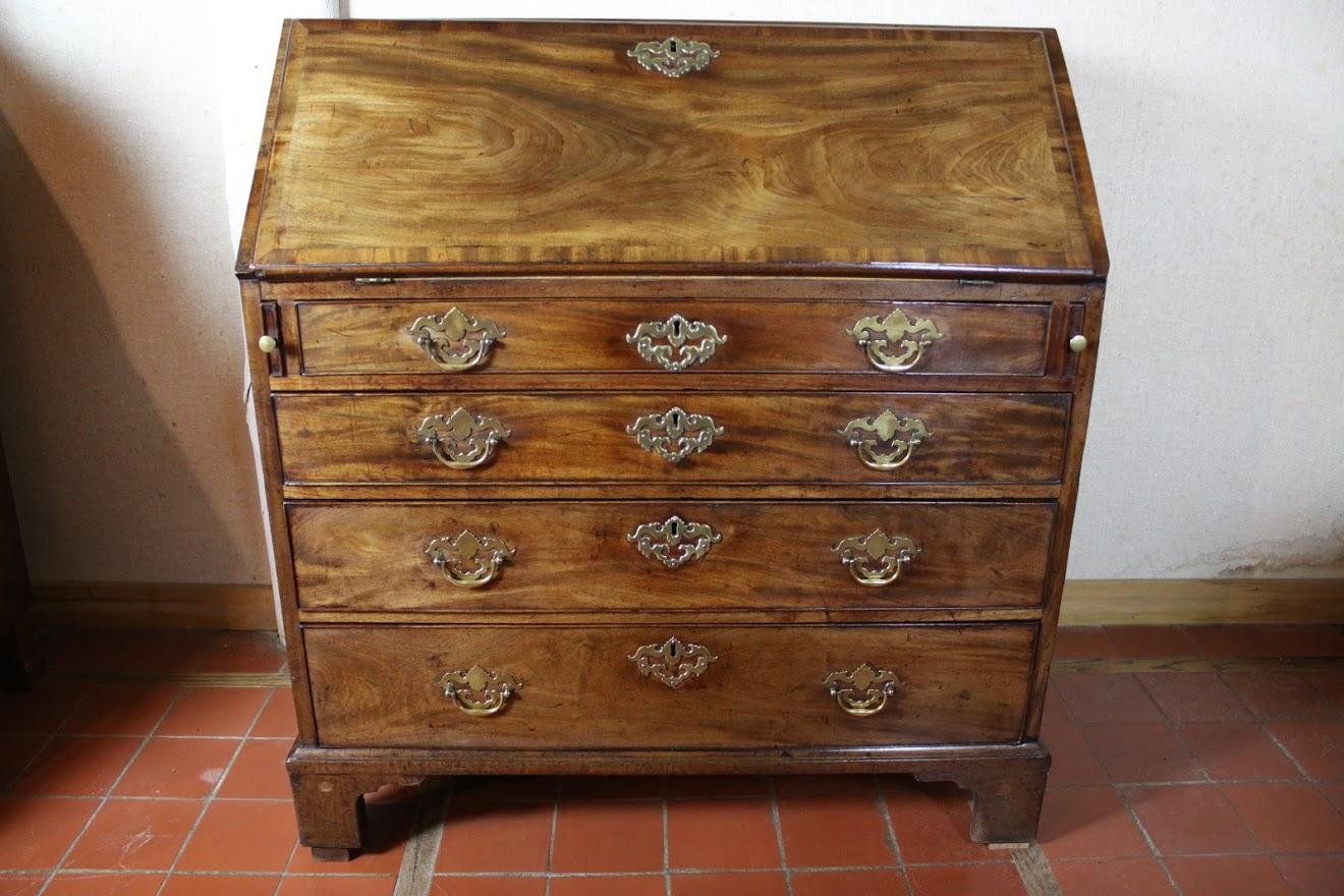 George III figured mahogany slant front bureau/desk. Fall has moulded edge and mahogany crossbanding above four graduated drawers with original locks and brass. Interior features prospect door with interior drawer, flanked by drawers and pigeon