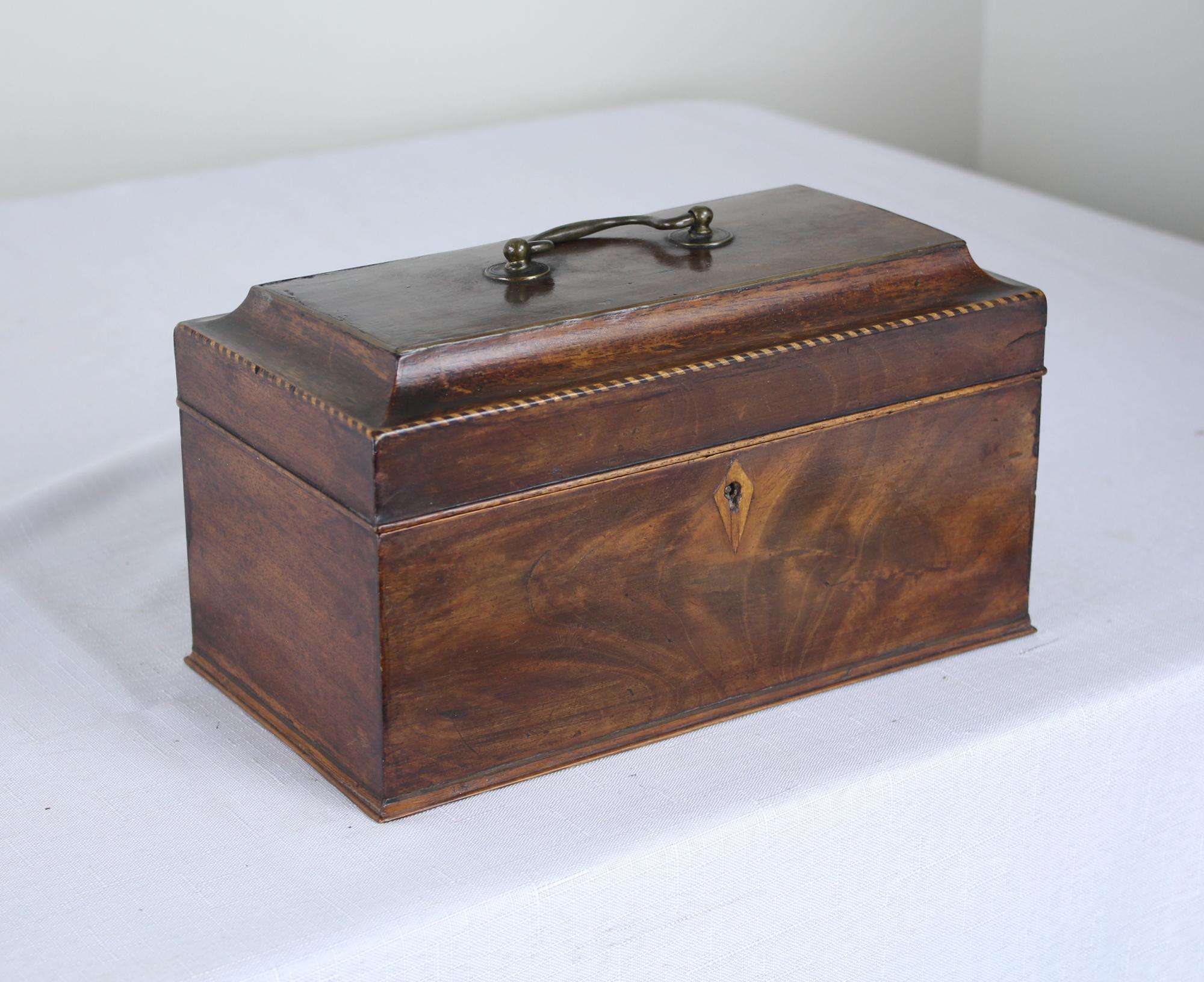 A splendid early sarcophagus shaped mahogany tea caddy with fanciful satinwood and ebony stringing about the top, circa 1780. Good color and patina and in very nice antique condition. The dividers in the interior have been replaced. No key.

