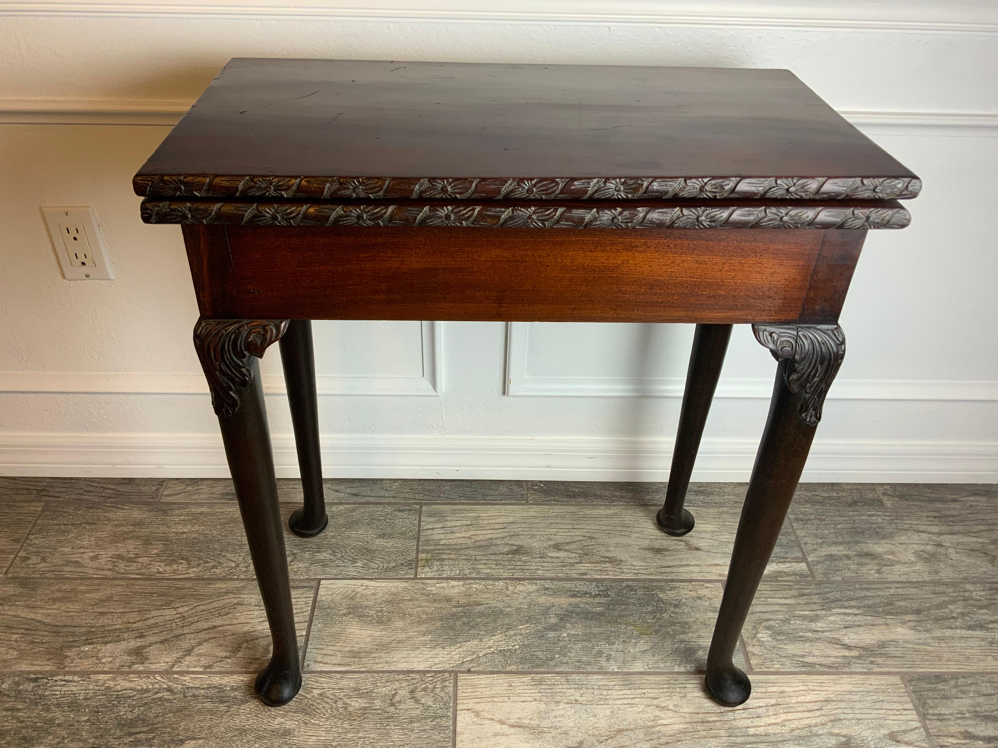 A very nice early Georgian Mahogany swing leg Tea or Card Table of diminutive proportions with carved knee cabriole legs ending in a pad foot.  Ribbon and blossom carved edge around the solid Mahogany tops.  Excellent color and patina on the