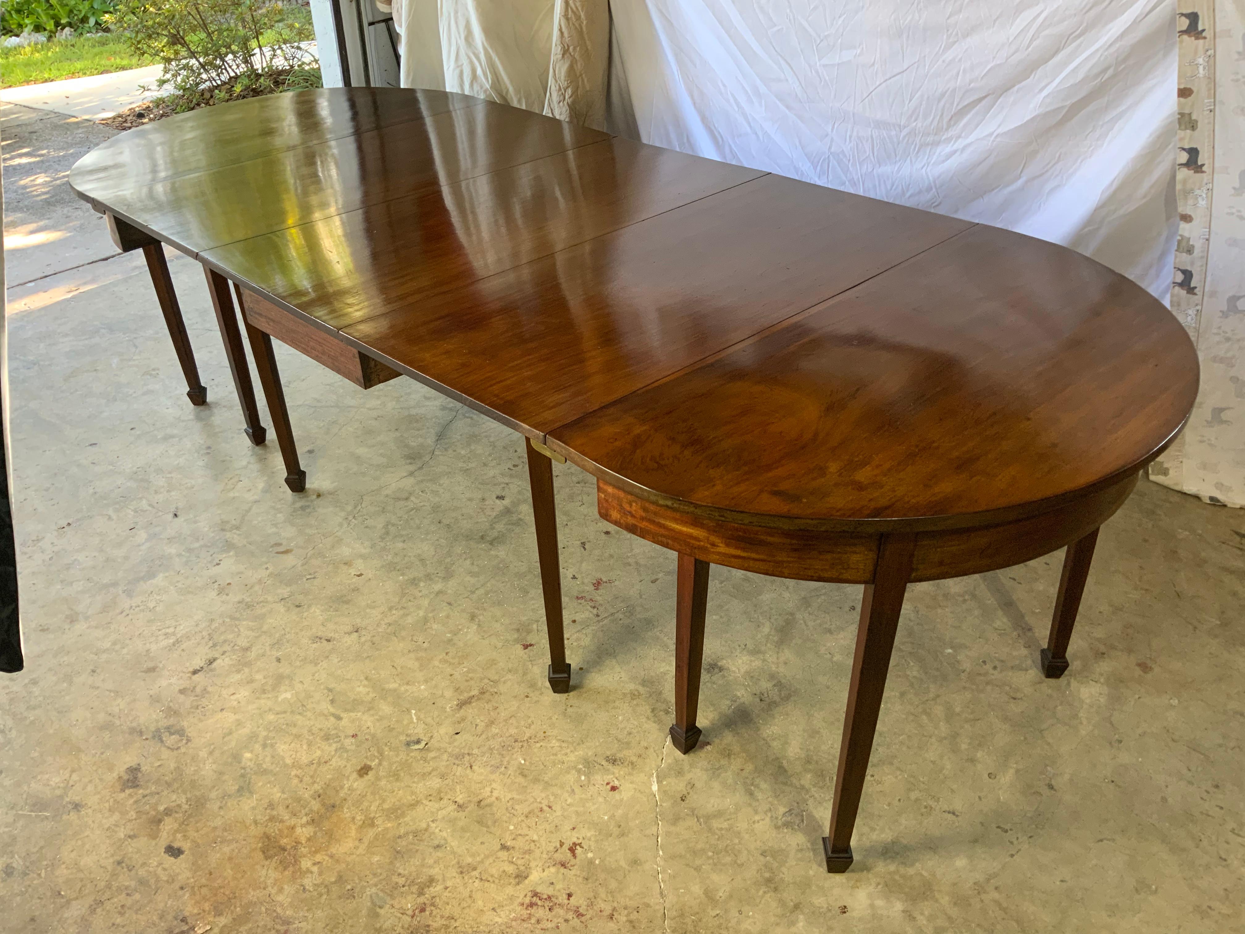 Very nice Georgian “D” end mahogany dining table in original surface with excellent color and patina on a nicely aged finish. Three piece table with tapered legs ending in spade feet. Drop leaf center section with swing out legs and two demilune