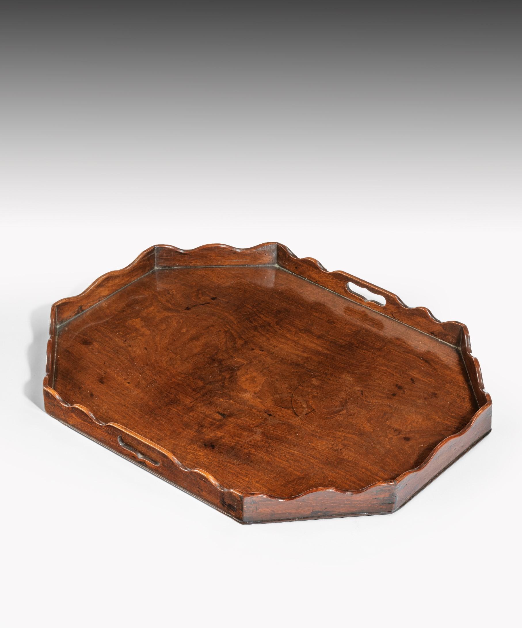 A Georgian mahogany tray; the tray is constructed from well figured mahogany with a shaped gallery pierced with two carrying handles. Retaining an excellent color and patination.
