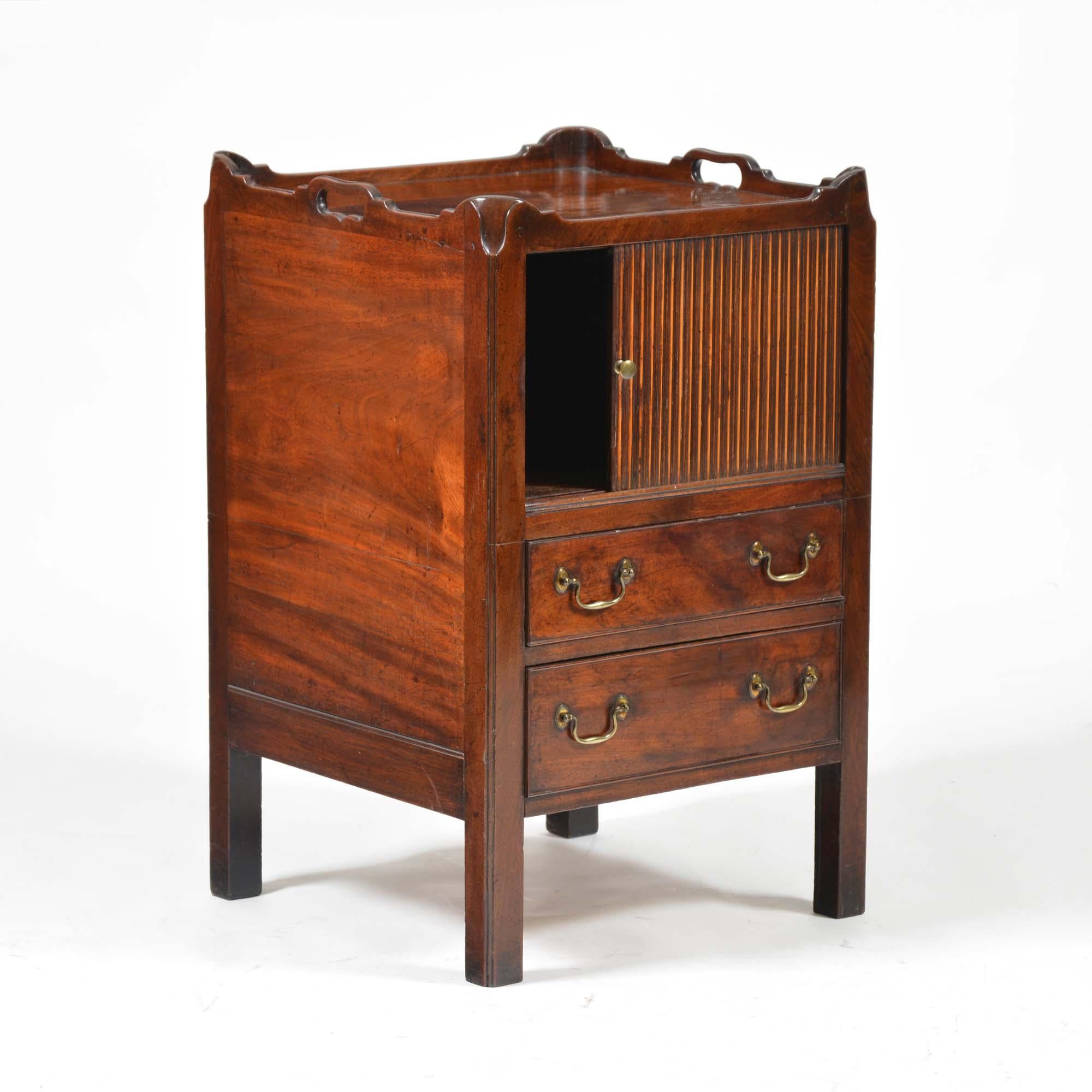 Georgian mahogany tray-top commode, the raised gallery pierced to the sides to form a pair of carrying handles. The inset top of well figured flame mahogany over a sliding tambour door above a pair of drawers with cock-beading and each with a pair