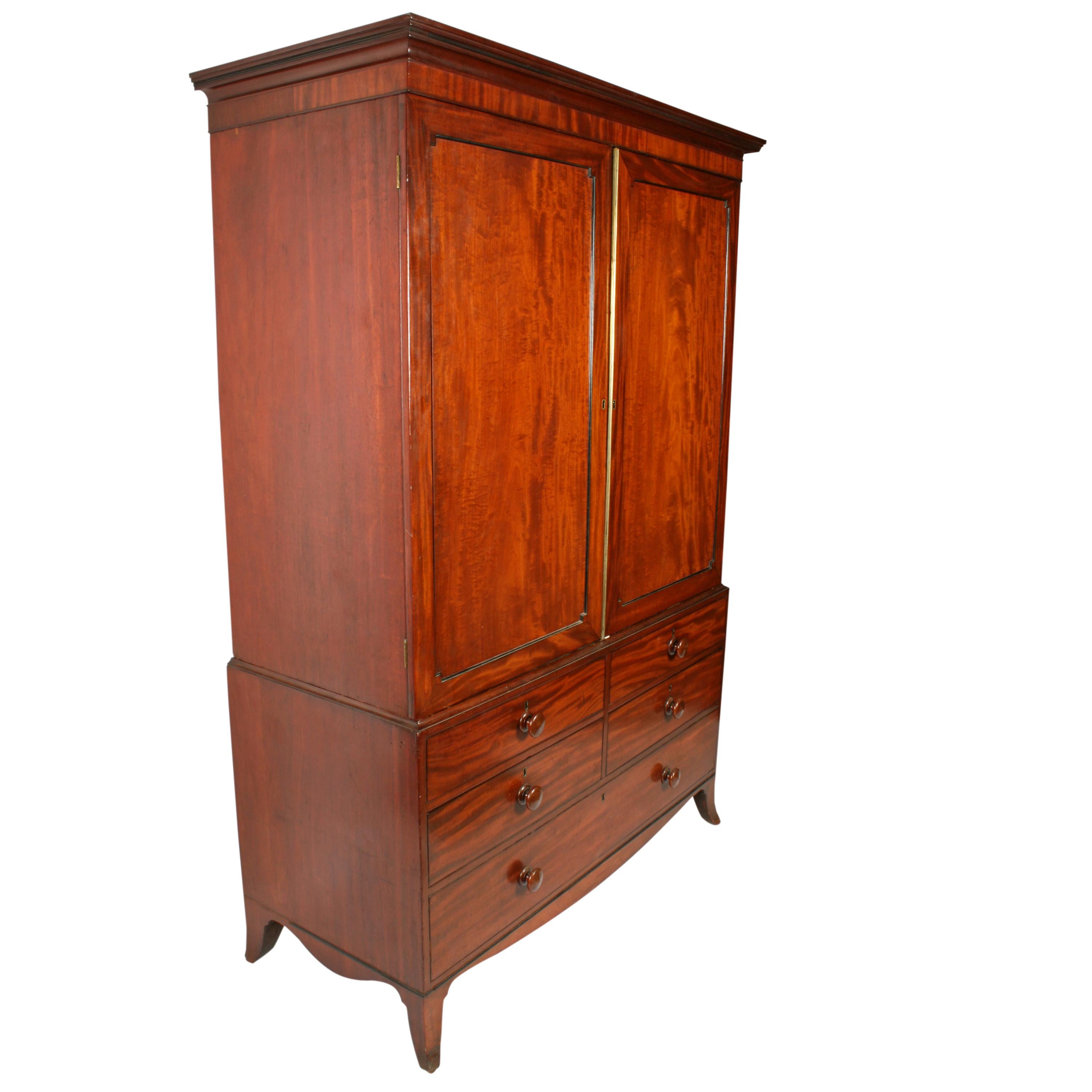 An early 19th century Georgian mahogany tray wardrobe with a drawer base.

The top has a pair of doors with recessed panels that are ebony edged and have a reeded gilt brass bead where the doors meet.

The inside holds five sliding trays that