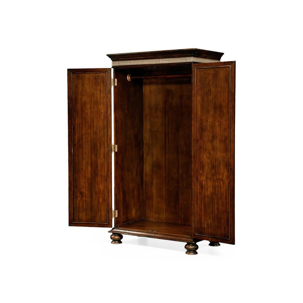 A fine English Georgian style Gentleman's wardrobe with crotch mahogany paneled doors on ornate brass return folding hinges and with satinwood crossbanding. Full width internal hanging rail, patinated brass pendant handles, the whole on large bun