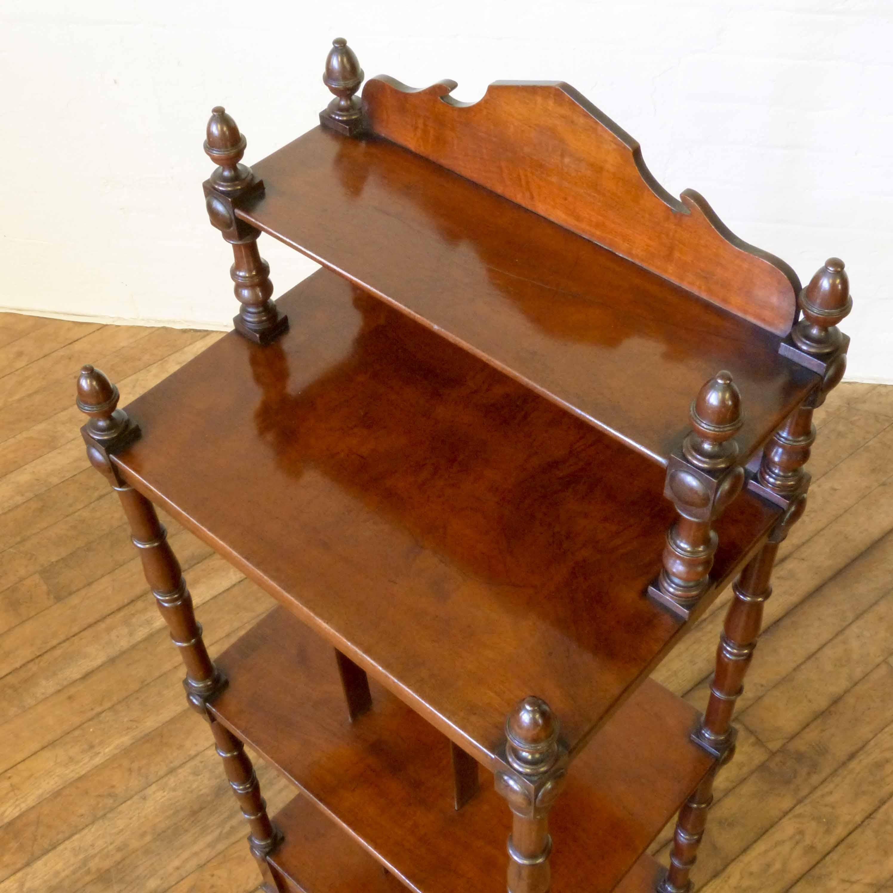 This is an attractive Georgian mahogany whatnot of small proportions. The drawer base is sat on turned legs that still retain their original castors, above which are two shelves and a ledged pediment. The turned supports all have acorn finials.