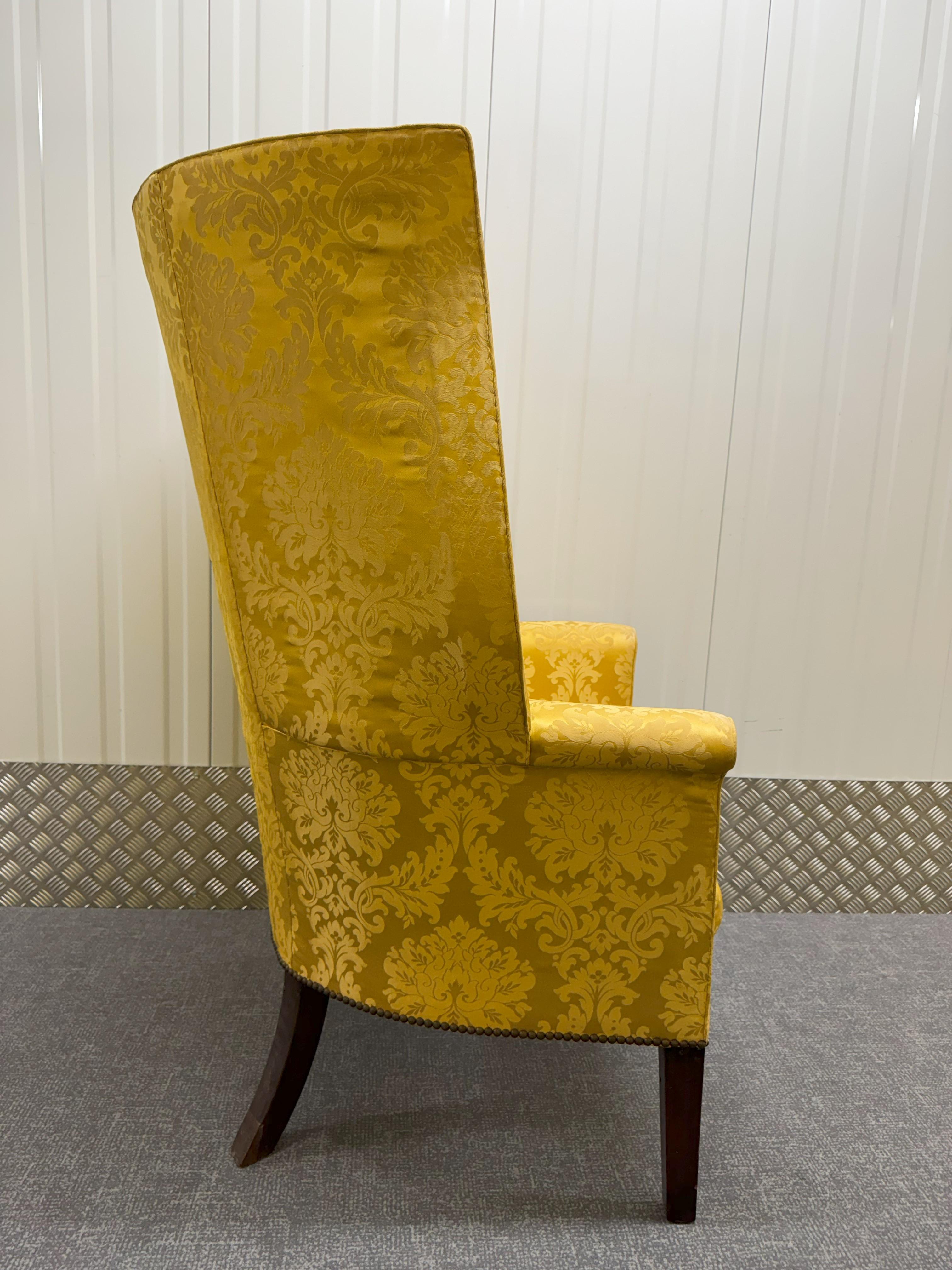 A Georgian mahogany framed wingback armchair upholstered in gold brocade on square tapering legs.