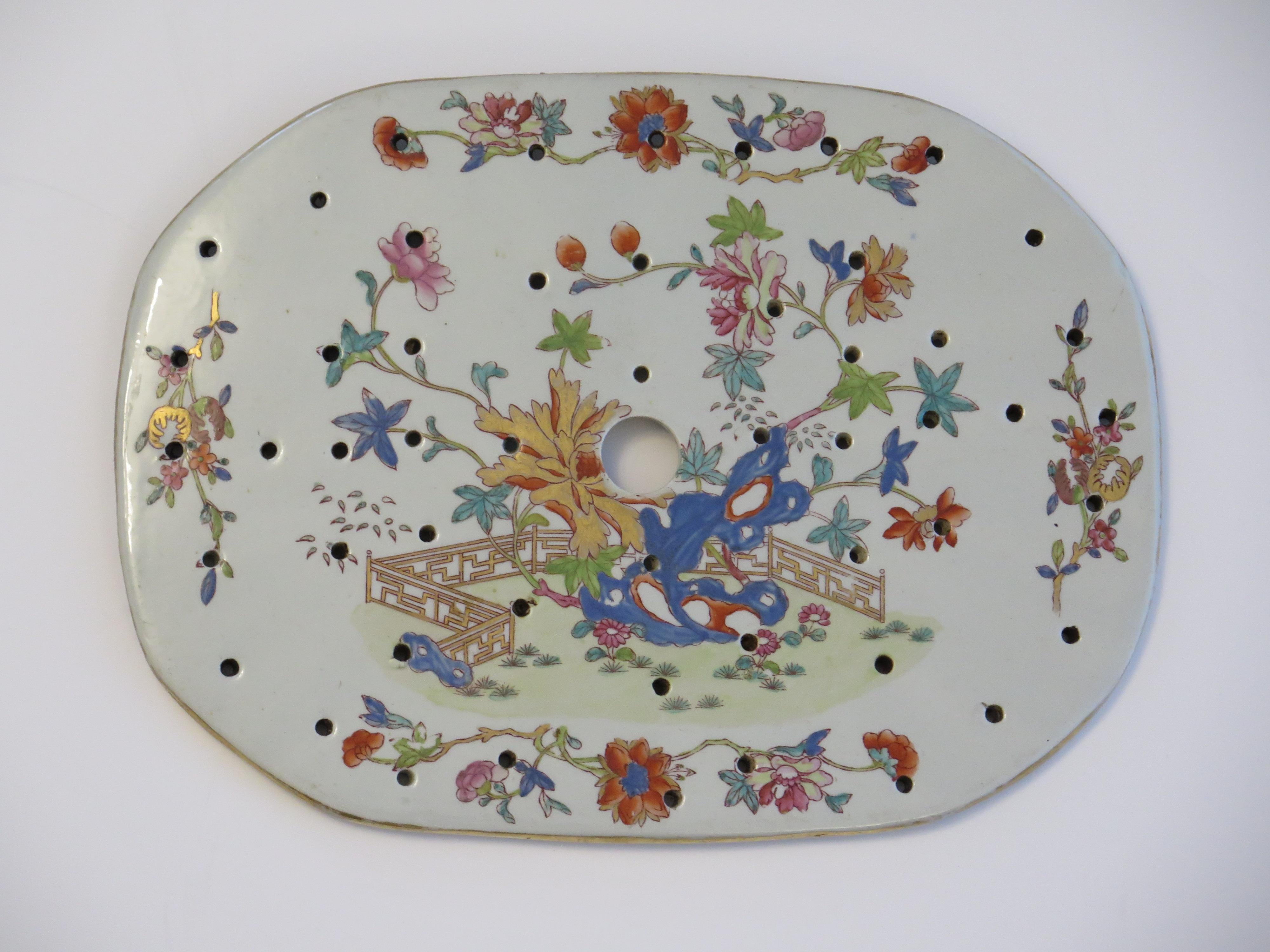 This is a very good hand painted Mason's ironstone Drainer or Strainer Plate, in the Fence, Rock and Tree gilded pattern, from their earliest George III rd period, circa 1818.

The piece is well potted with an oval / octagon shape having one large