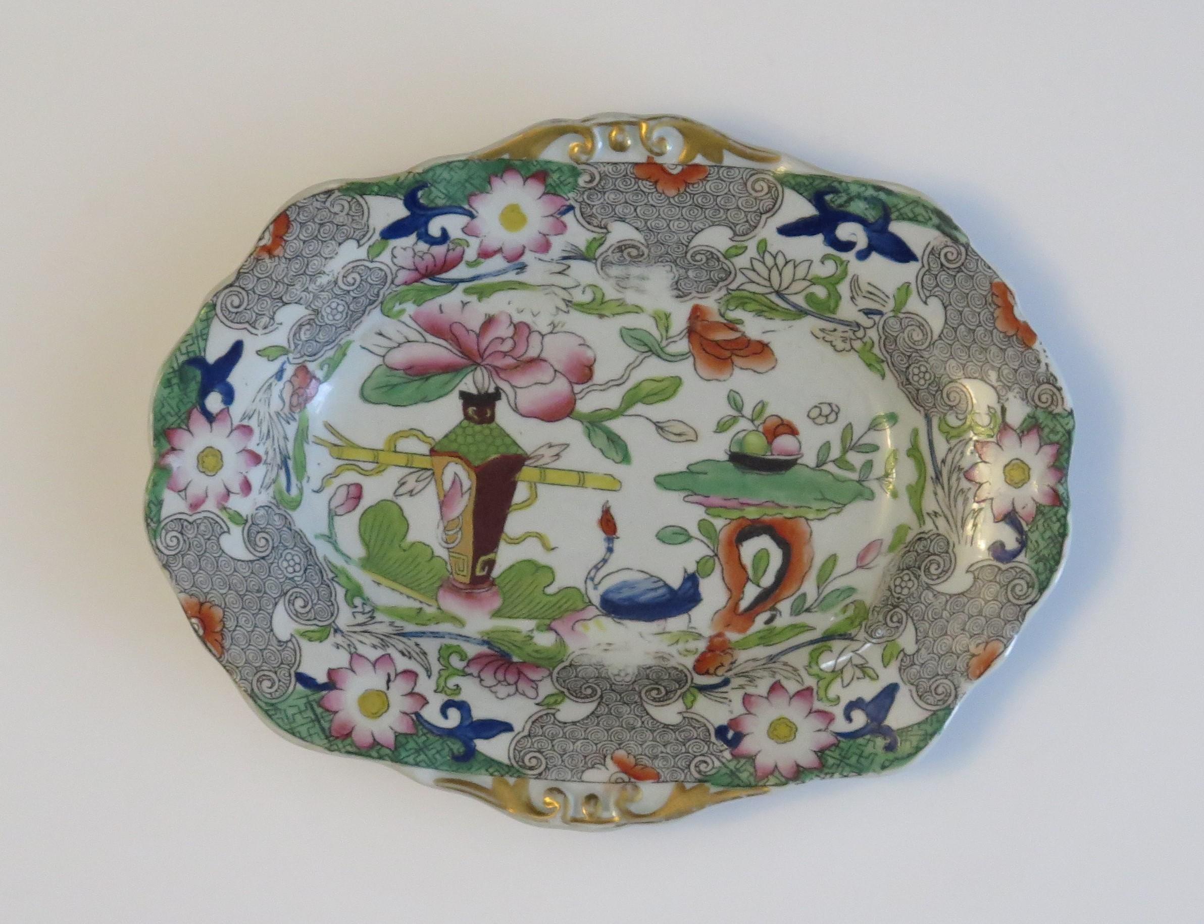 This is a good hand painted Mason's ironstone small oval dish, in the table and flowerpot gilded pattern, from their earliest George IIIrd period, circa 1818.

The piece is well potted with a small oval shape having moulded edges and standing on a
