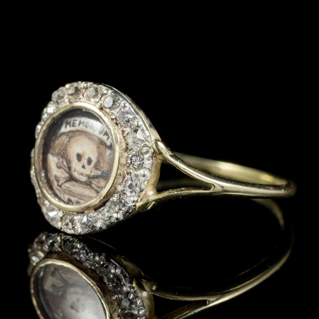 This remarkable Memento Mori ring features a Crystal window with a hand painted Enamel skull and crossbones underneath with the words ‘Memorium’ written above. 

Memento mori is Latin for ‘Remember that you have to die’. During the 17th Century