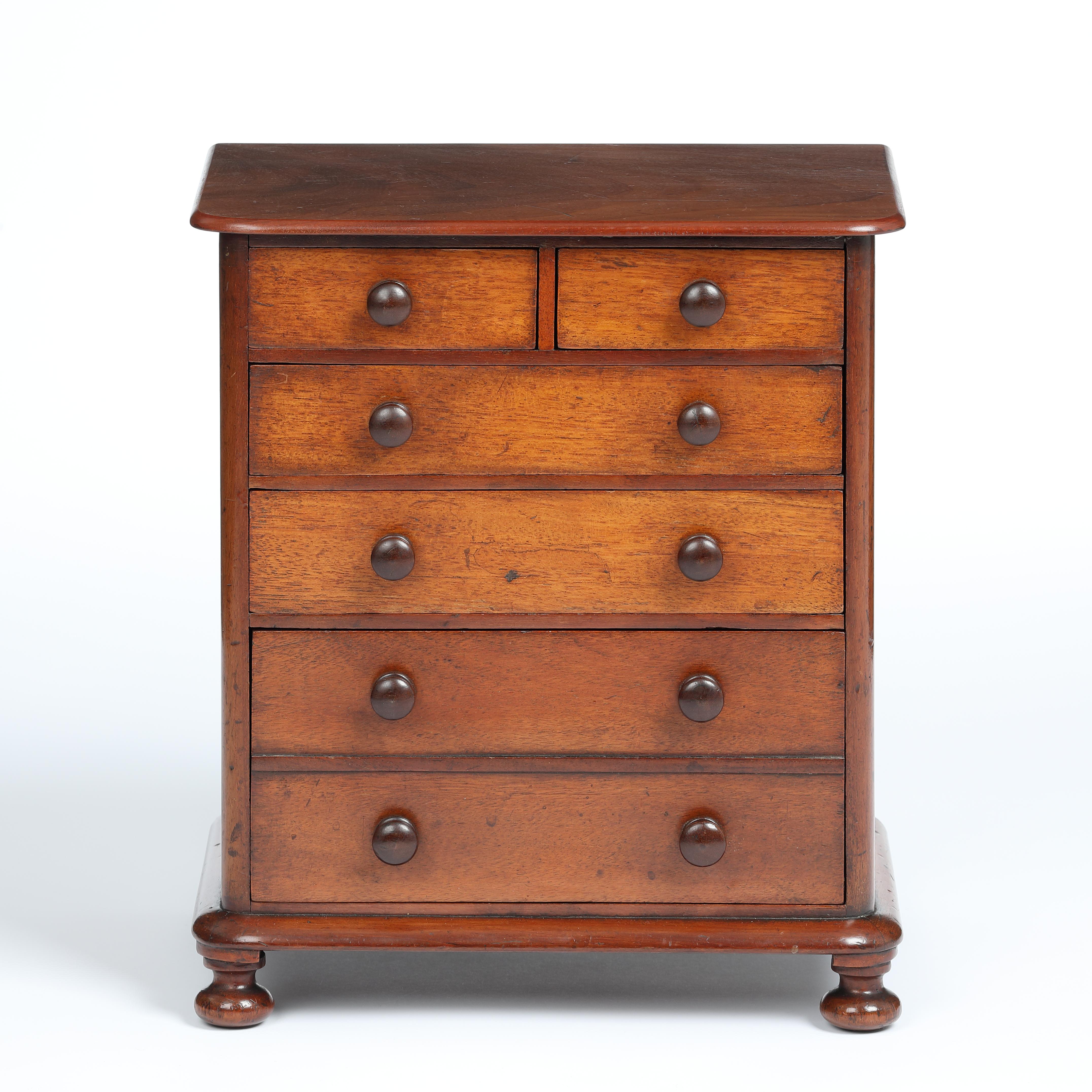 A fine quality and well proportioned mahogany miniature chest of five long graduated drawers in fine original condition. Superbly constructed with the neatest, tiny dovetail joints to the cedar wood lined drawers, which have chamfered-edge bottoms
