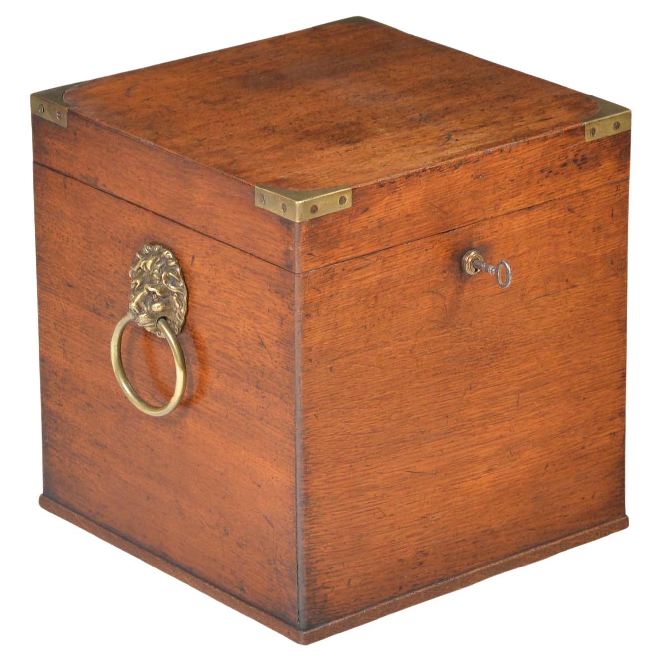 Georgian oak cellarette, the lid with cast brass corner mounts to protect the corners in transit,  opens with Bramah type lock with key, the interior with divisions to accommodate four bottles or decanters. To the sides a pair of cast brass lion’s