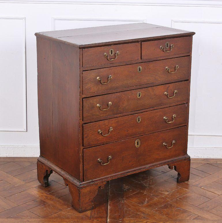 English Georgian oak chest of drawers, converted from a slant-front bureau. Two half-drawers on the top, followed by three drawers of equal height, and a bottom drawer of larger size. All highlighted nicely with original brass hardware. 



  