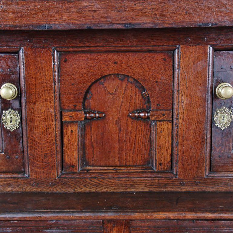 A late-17th-early 18th century solid oak ‘court cupboard’, the top with two small doors flanking a centre panel, the base having a larger two-door cabinet with a pair of upper drawers. A handsome early country piece with lovely color and original