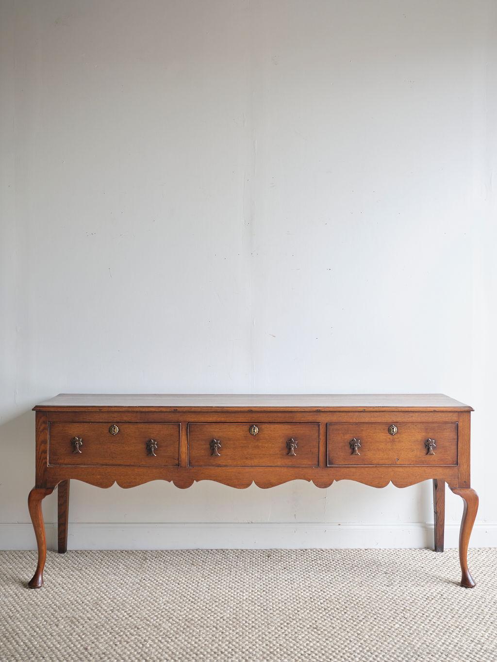 A lovely Georgian oak dresser that would make a unique, yet classic addition to any home or office. It features 3 medium sized drawers and a dark and warm patina. The brass hardware is in great condition. Each drawer has a key hole, but this dresser