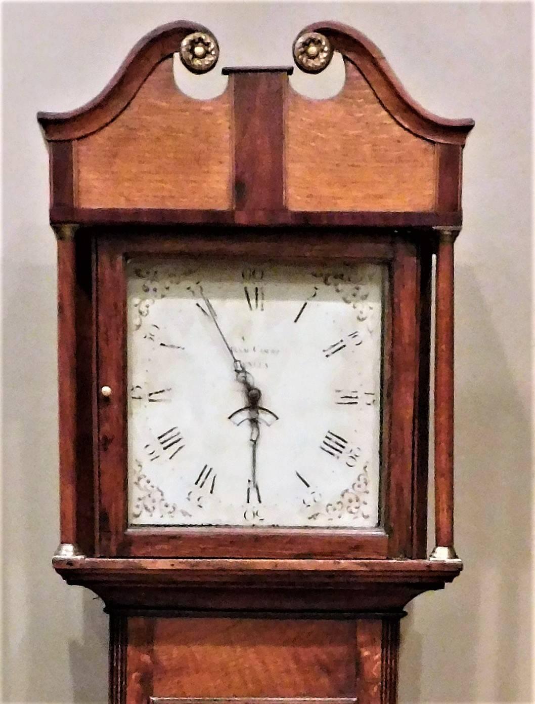 This small long case clock was made in Henley in Arden, Warwickshire of English. One-day clock with a single weight (wound by pulling chain). Chimes on the hour. The enameled face has Roman numerals, decorative flourishes, and the maker's name and
