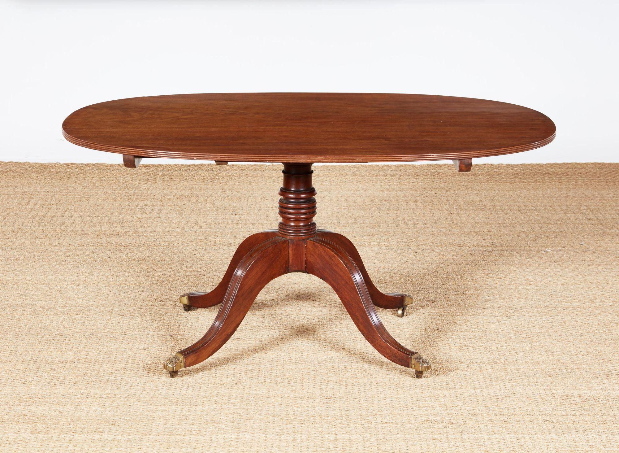 Fine George III period mahogany oval breakfast table, the single plank top with rich fiddle back graining and with reeded edge, over tilt top pedestal base having bold ring turned shaft and standing on downswept reeded legs with original paw feet