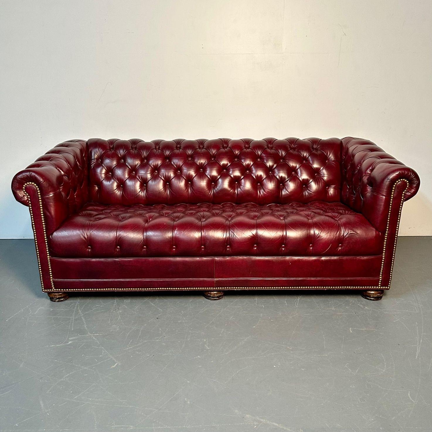Georgian Oxblood Red Leather Chesterfield Sofa / Settee, Tufted, Bun Feet
 
Very nice Georgian style chesterfield sofa having a tufted red oxblood upper sitting on 6 brown mahogany bun shaped feet. The entire back, armrests, and seat cushion is