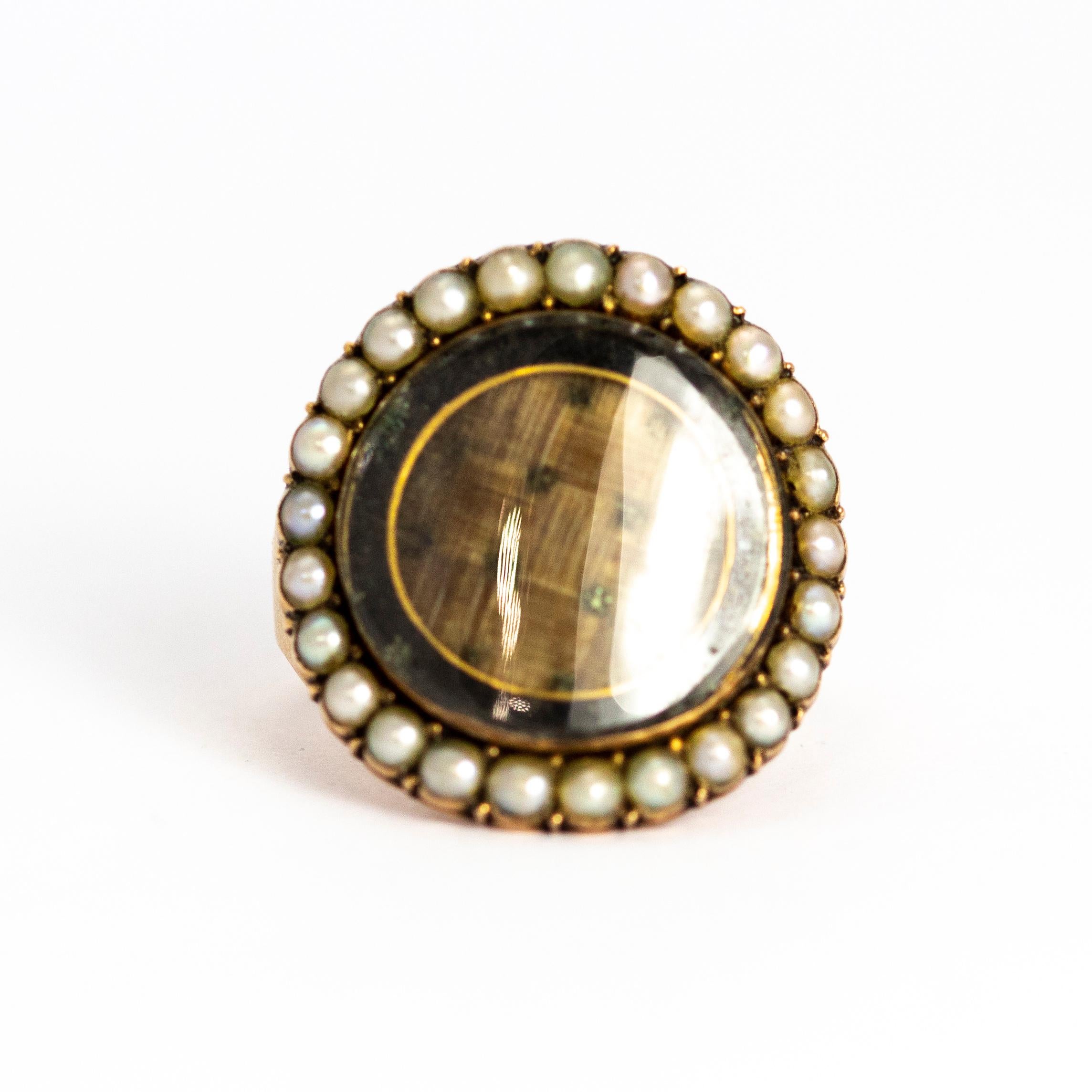 A superb antique Georgian mourning ring. The large circular glazed locket front is set with woven hair and black enamel, bordered with beautiful pearls. Modelled in 9 karat yellow gold. The inscription on the inside of the band reads 