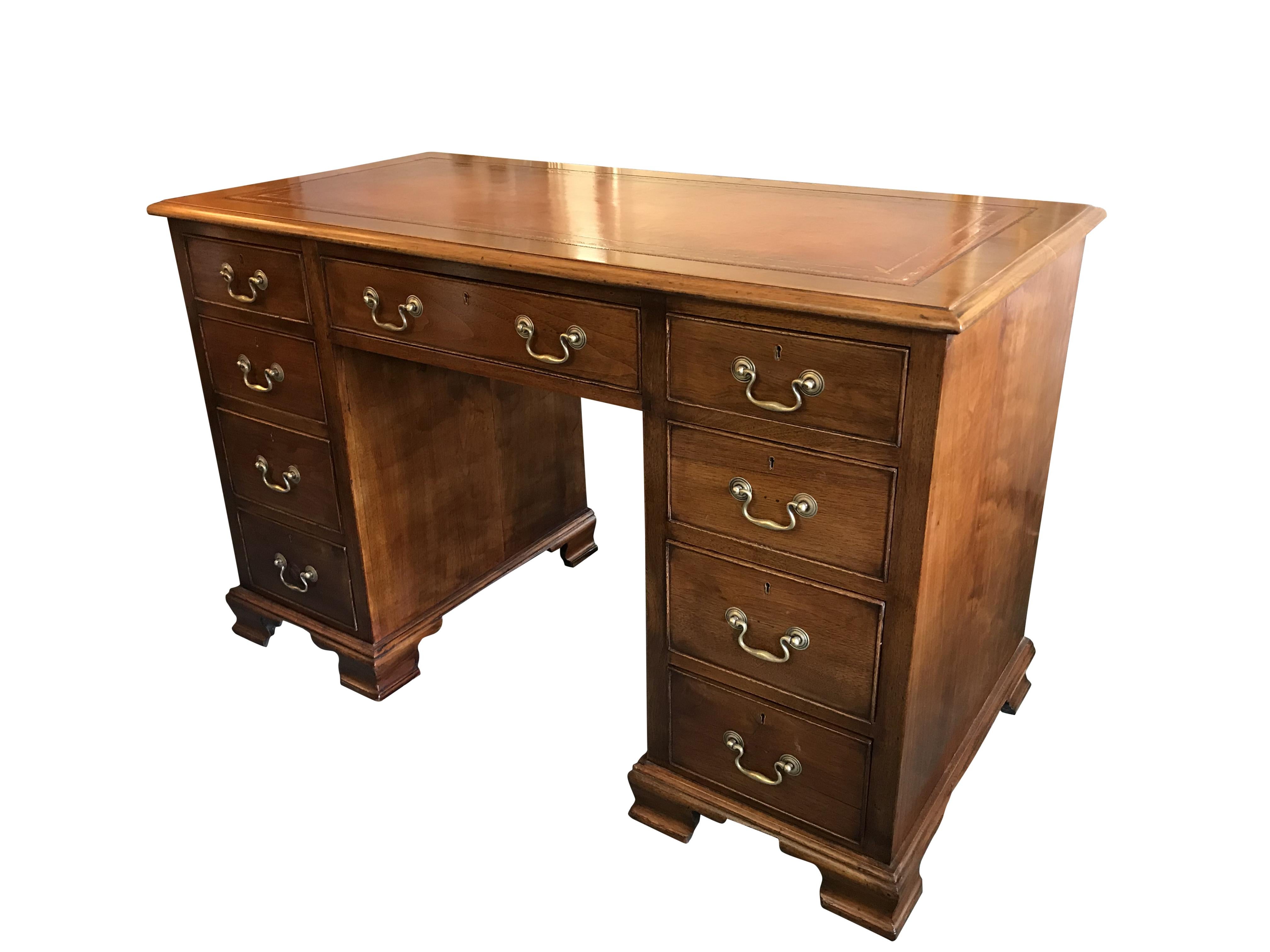 1920s Georgian style twin pedestal one piece kneehole desk with swan neck handles and nine deep drawers, ending on ogee feet. Leather top with gilt tooling is in immaculate condition, as recently replaced by a master craftsman. 

All locks in good
