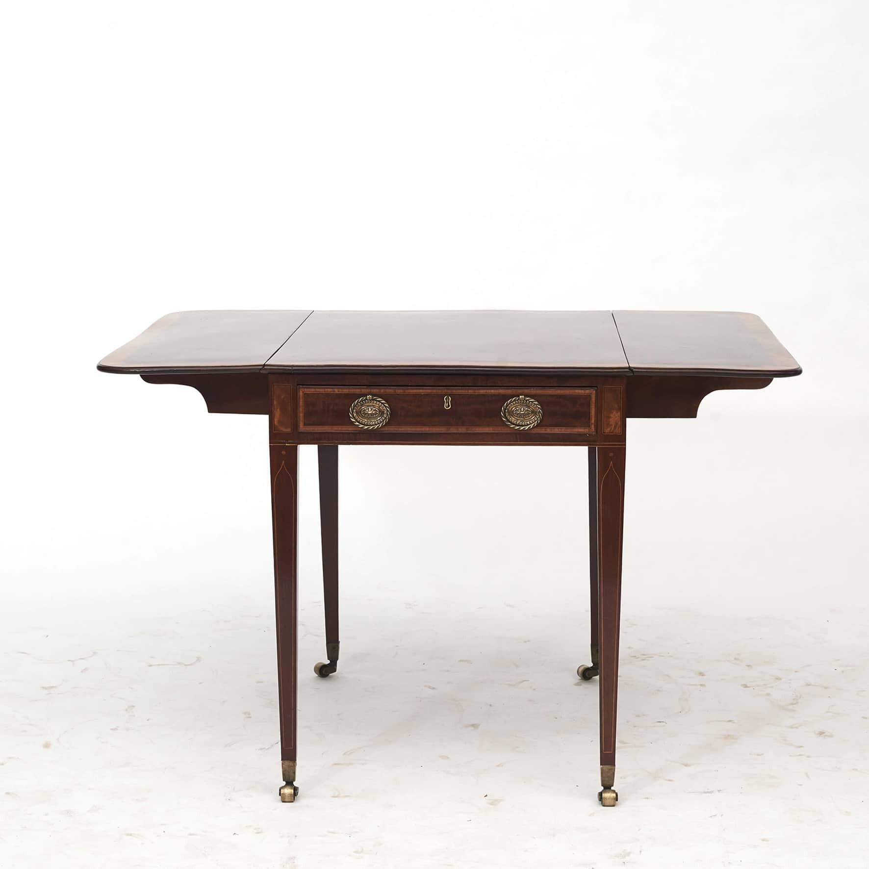 Georgian Pembroke table with a drawer.
Made of mahogany with inlaid satin wood in the form of a wide edge on the table top and drawer.
Furthermore, line marquetry in satin wood and ebony on table top, drawer and legs.
Original bronze fittings and