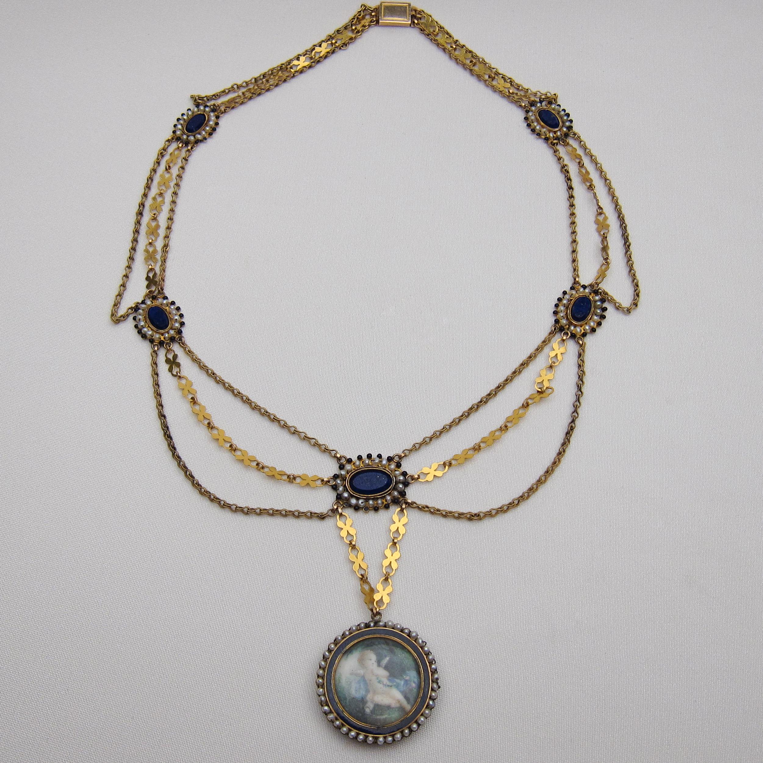 Circa 1790. This fantastic fancy link 18KT gold swag necklace features a round pendant measuring 25mm in diameter and hand-painted with a cherub (putto) scene. The pendant is encircled by a 2mm wide blue enamel strip, seed pearls, and blue glass