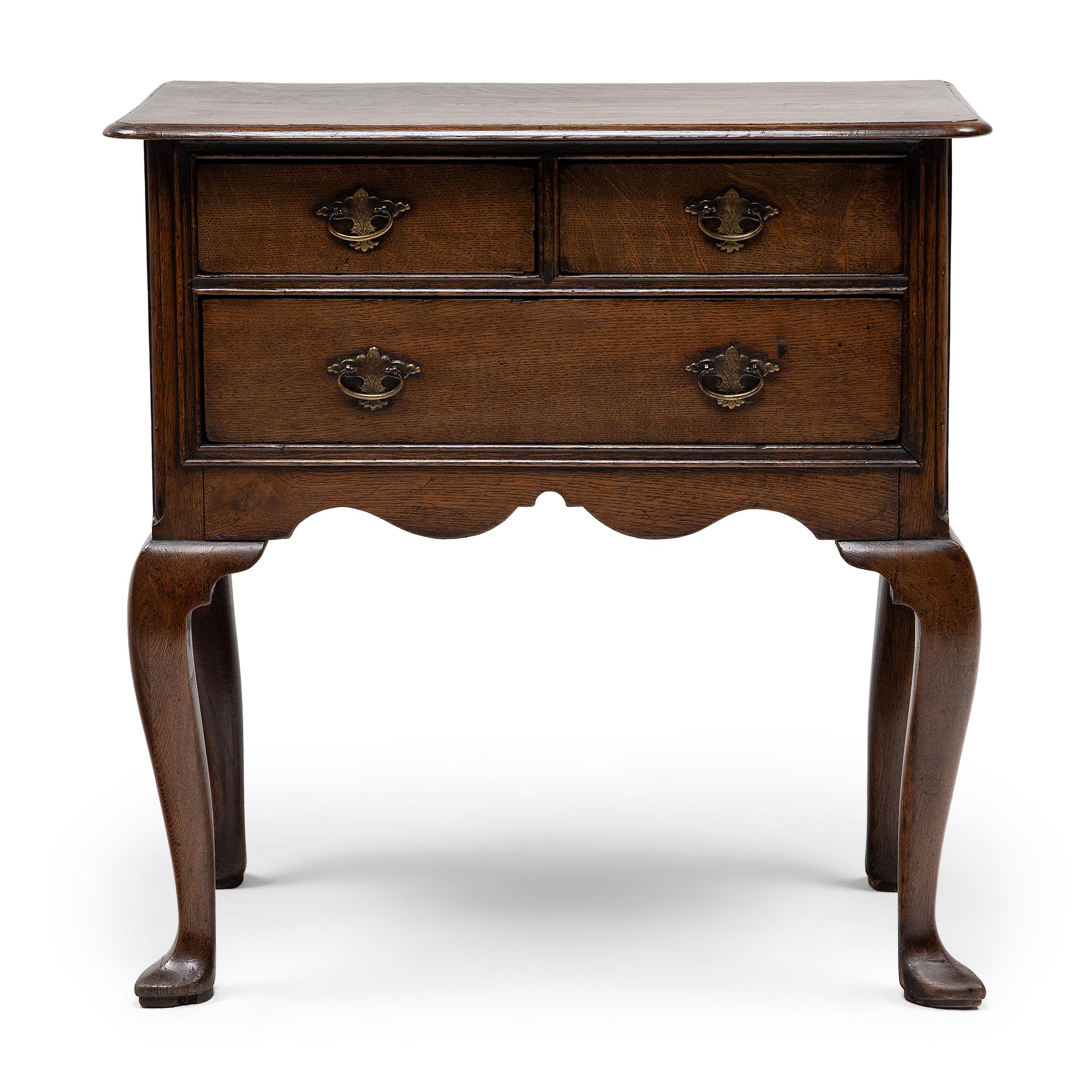 This English lowboy table from the mid-18th century unites the refined flourishes of Regency-era furniture with the timeless appeal of country antiques. Crafted of English oak, the table features two short drawers above one long drawer, a thin,