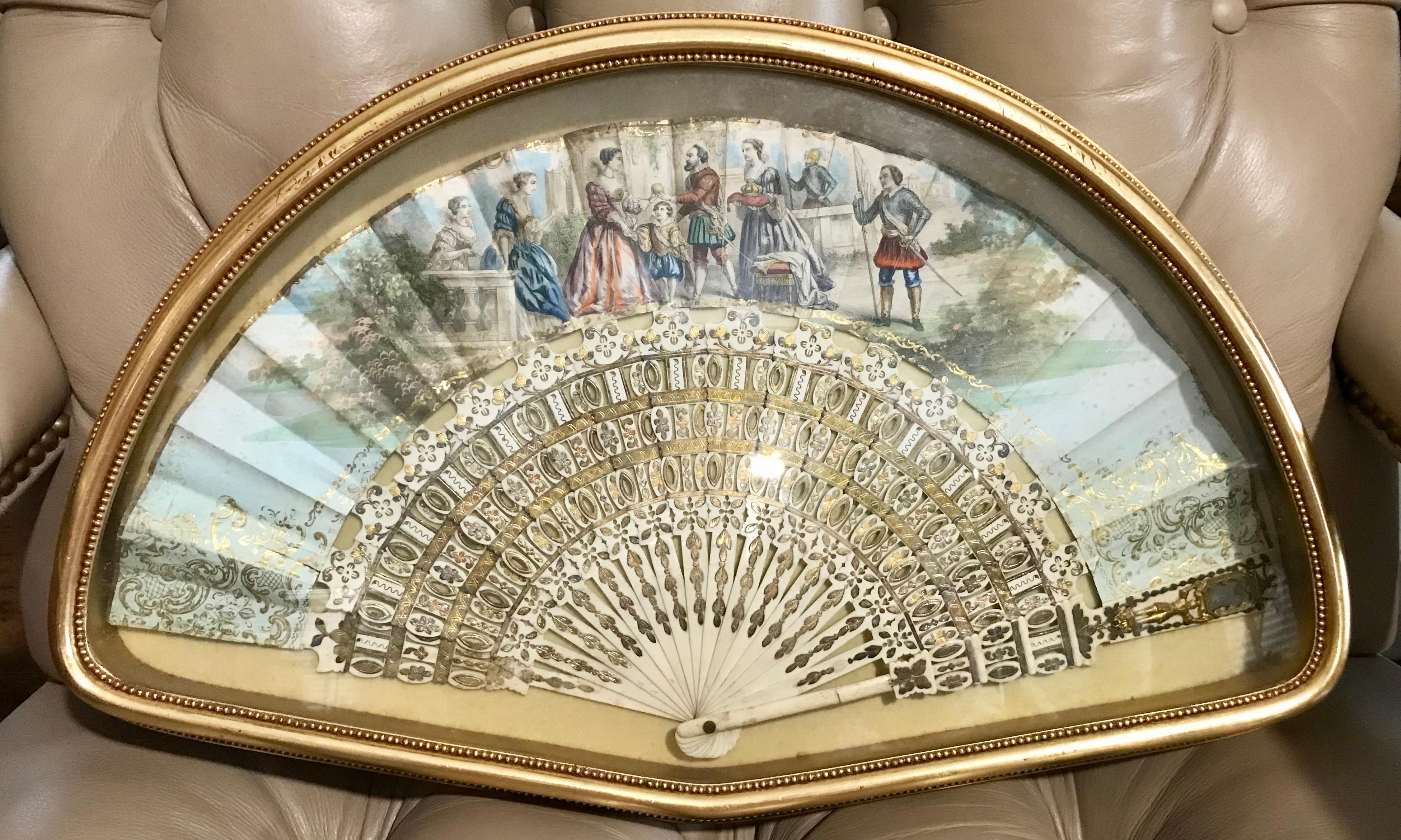 Superior quality painted with regal figures bearing a crown and gifts,
perhaps commemorating a royal event.
The fan is accented with gilt appointments and the 16 arm bone
framework is lavishly gilded and pierce carved. 
The fan is housed in a