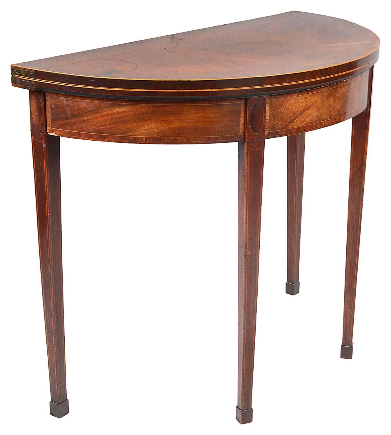 A good quality Georgian period mahogany demilune card table, having a lovely faded patina, satinwood crossbanding to the top and frieze. Opening to reveal an inset baize covered card playing table. The double hinged leg action to the back supporting