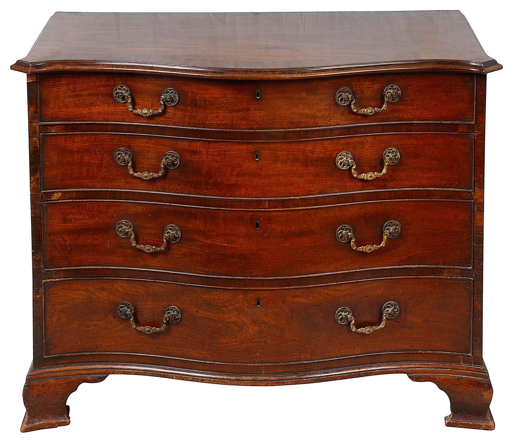 A very good quality late 18th Century mahogany serpentine fronted chest of drawers, having a good original patina, a crossbanded top, the original brass pierced swan neck handles, cock needed drawers, the top drawer fitted with a brushing slide and