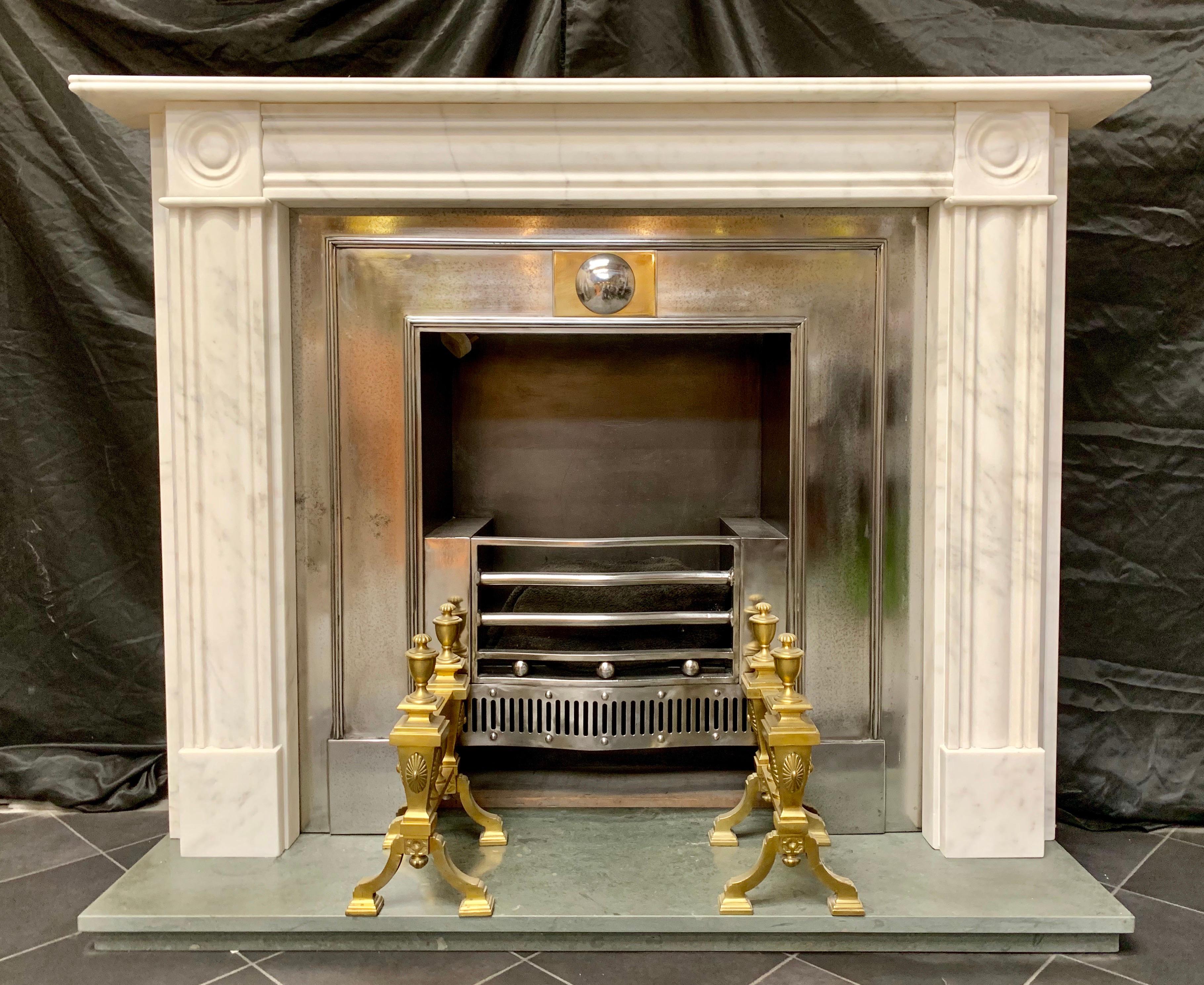 A charming Georgian period style lightly veined statuary marble bullseye fireplace surround, a reeded shelf sits directly above a moulded frieze, flanked by a pair of well carved bullseyes with spacer capping, supported by slender moulded jambs