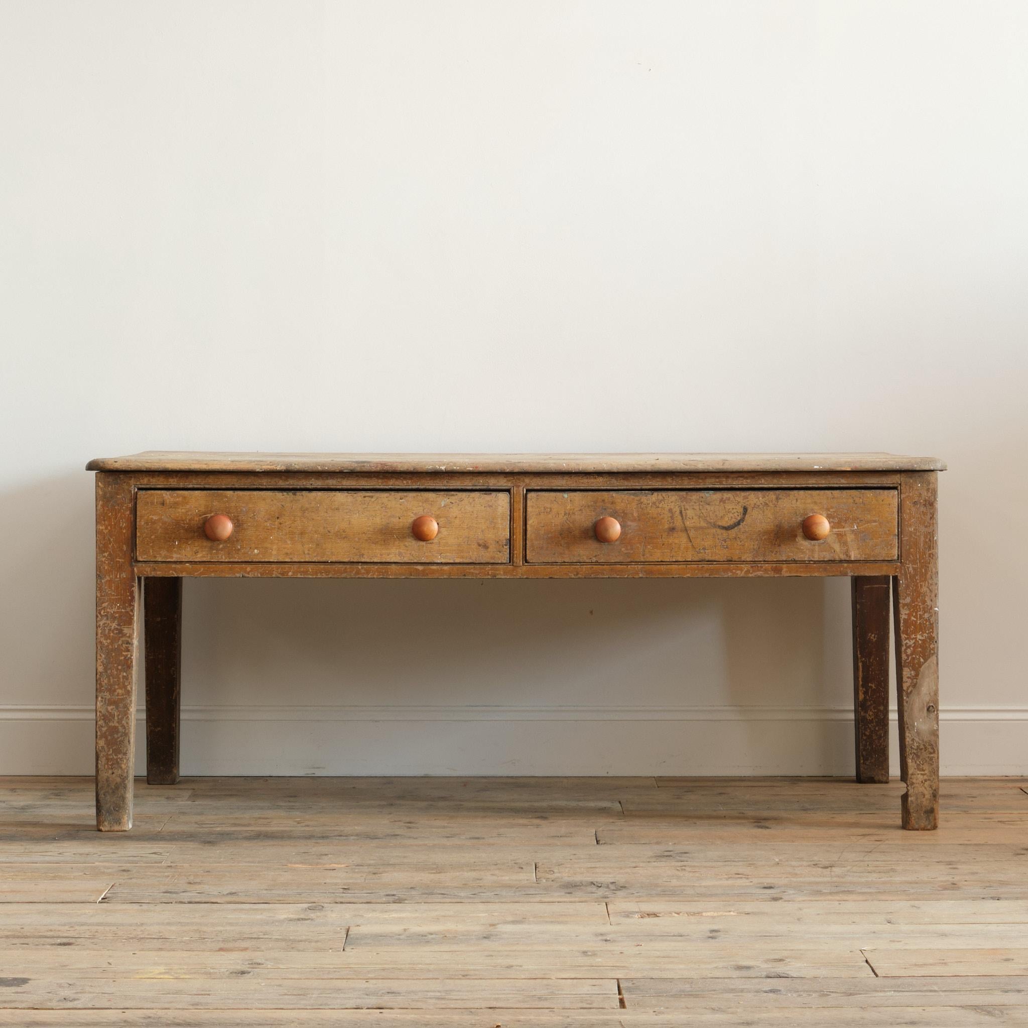 A Georgian pine scullery table in its original simulated golden oak grained paint and 2 plank top. The 2 wide drawers run the full depth of the table and run well. In all but original condition with a dry and beautifully worn surface. We have