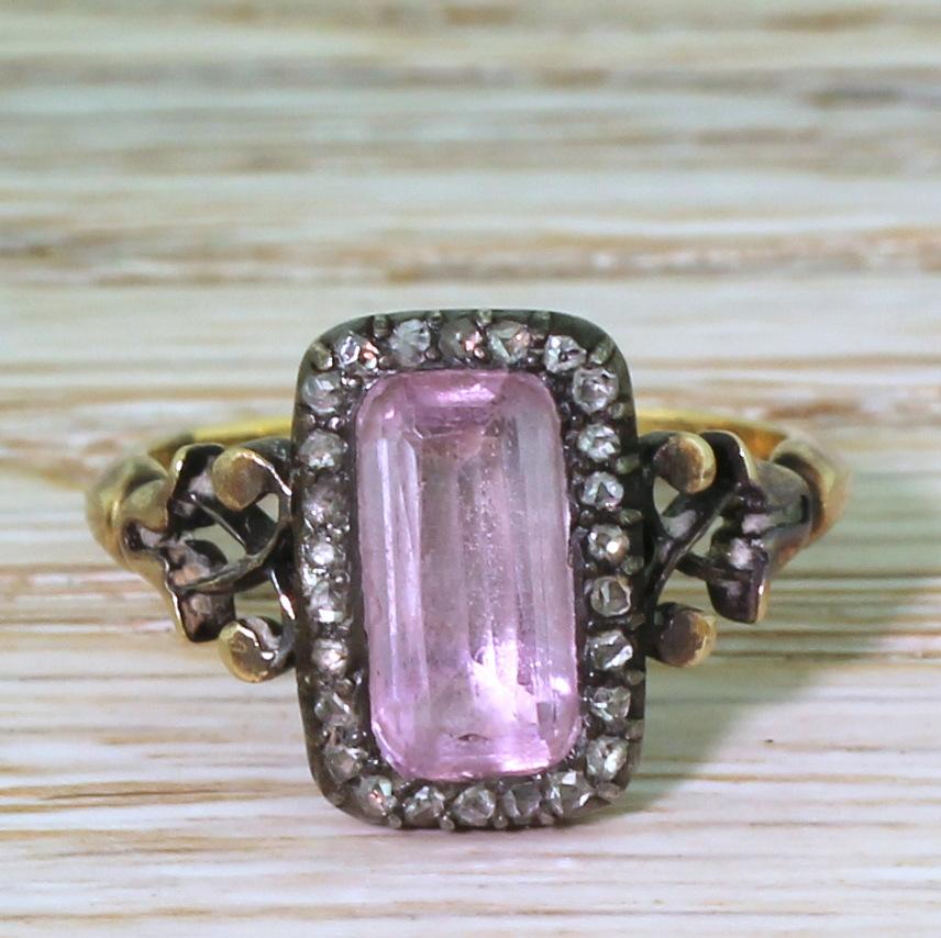 A Georgian ring that is as much a piece of history as it is an item of jewellery. At the centre is a long, lozenge shaped topaz in a closed-back setting that displays a soft purplish pink hue, surrounded by twenty-six rose cut diamonds in cut-down