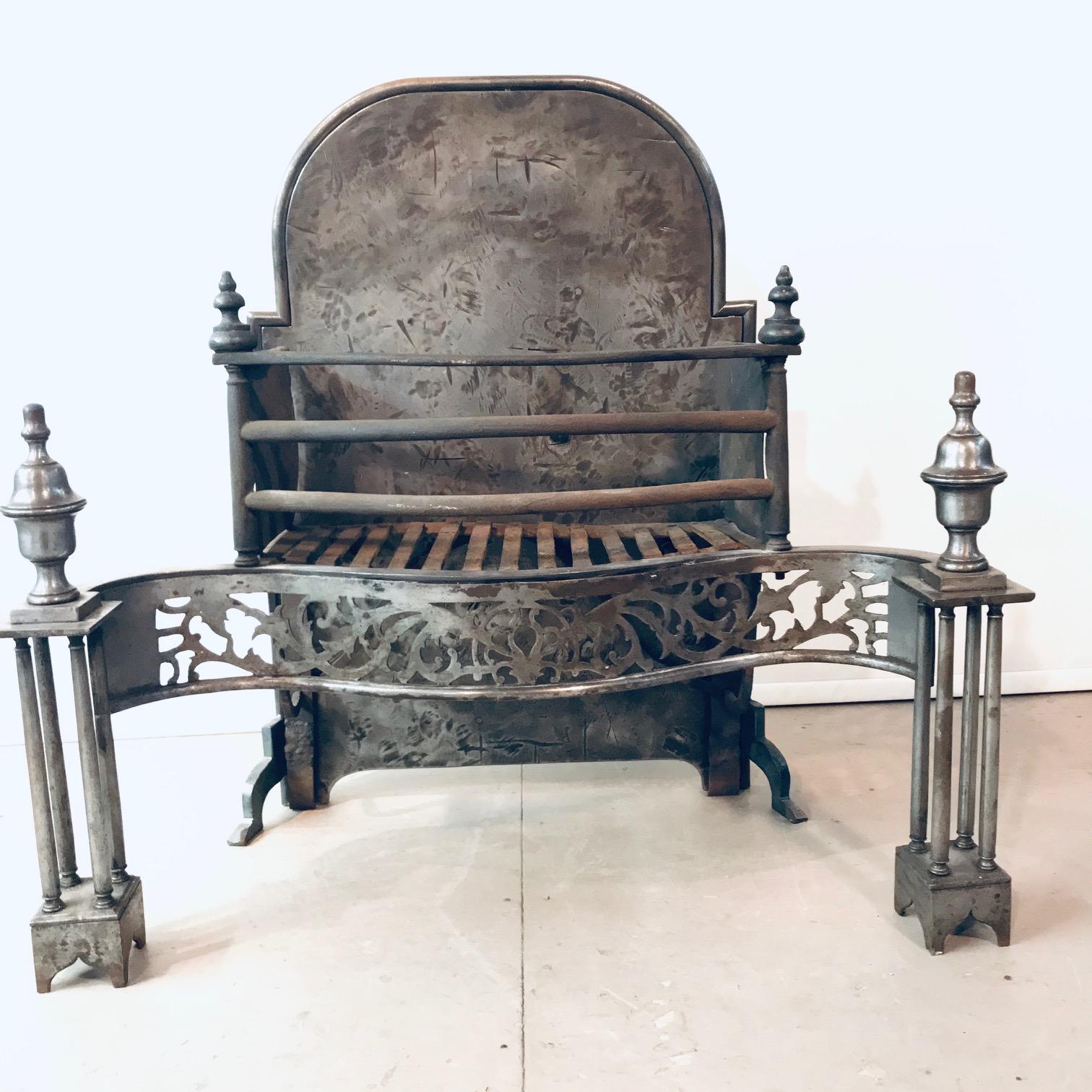 This fine grate is an ideal size for domestic use. The serpentine shape is especially desirable. The fire basket is flanked by a pair of columnar pedestals with large finials, and has a beautiful applied frieze with pierced cutwork decoration.