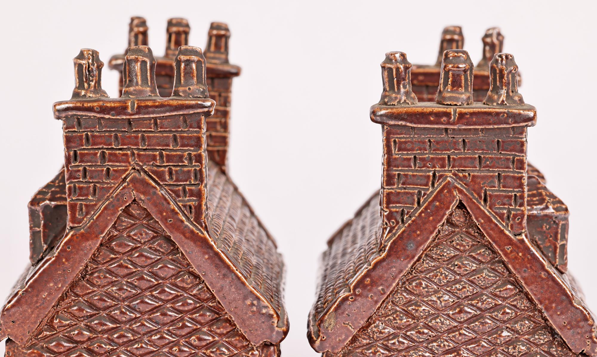 A rare and large pair Georgian English treacle glazed stoneware cottage money boxes dating from the early 19th century. The large cottage money boxes are finely crafted with a step leading to the front door, with two windows and two triple chimney