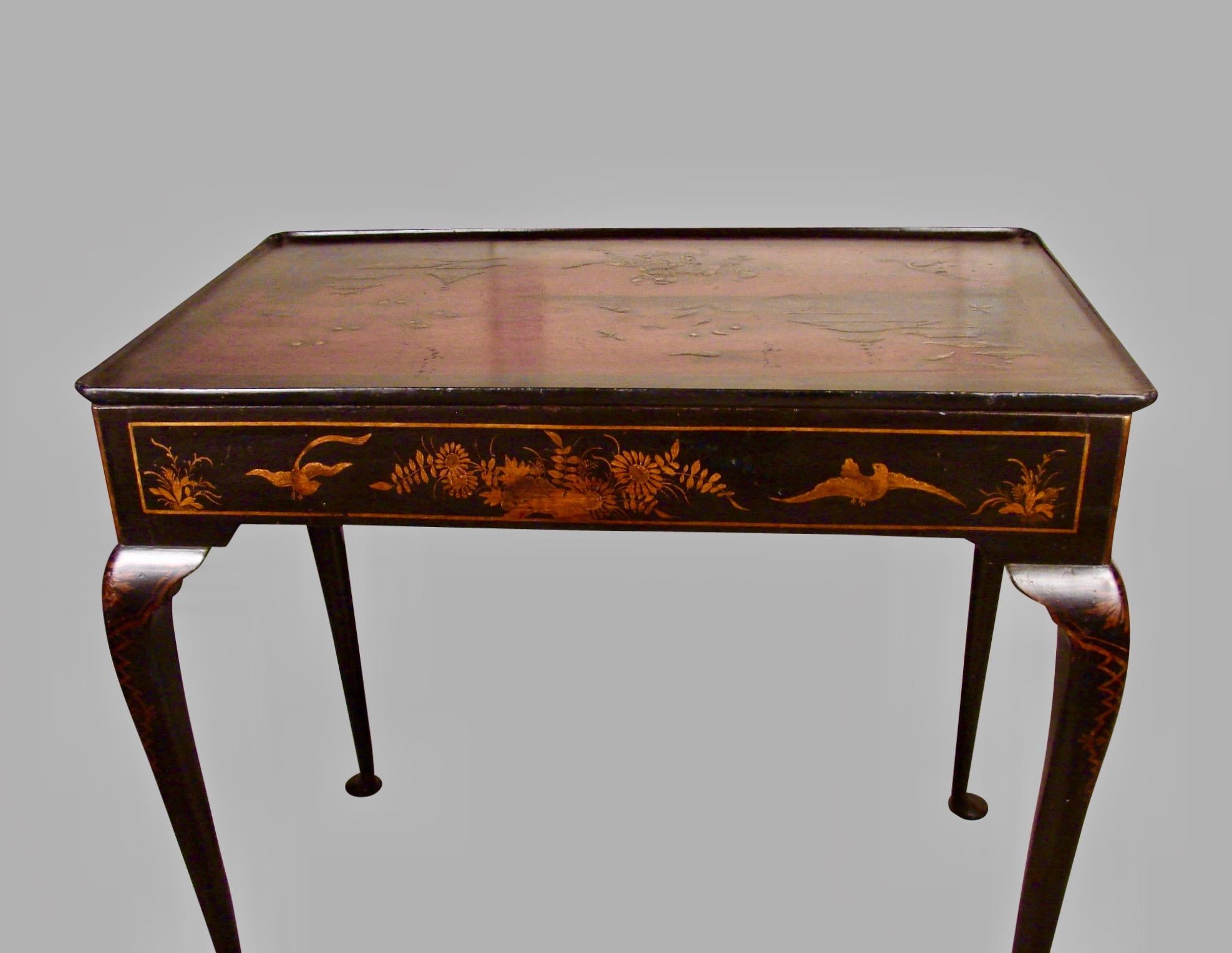 A lovely George III period red and black japanned side table, the dished top depicting an elaborate landscape with birds, butterflies and a figure on horseback, the background depicting pavilions in a garden setting, framed by a gold and black