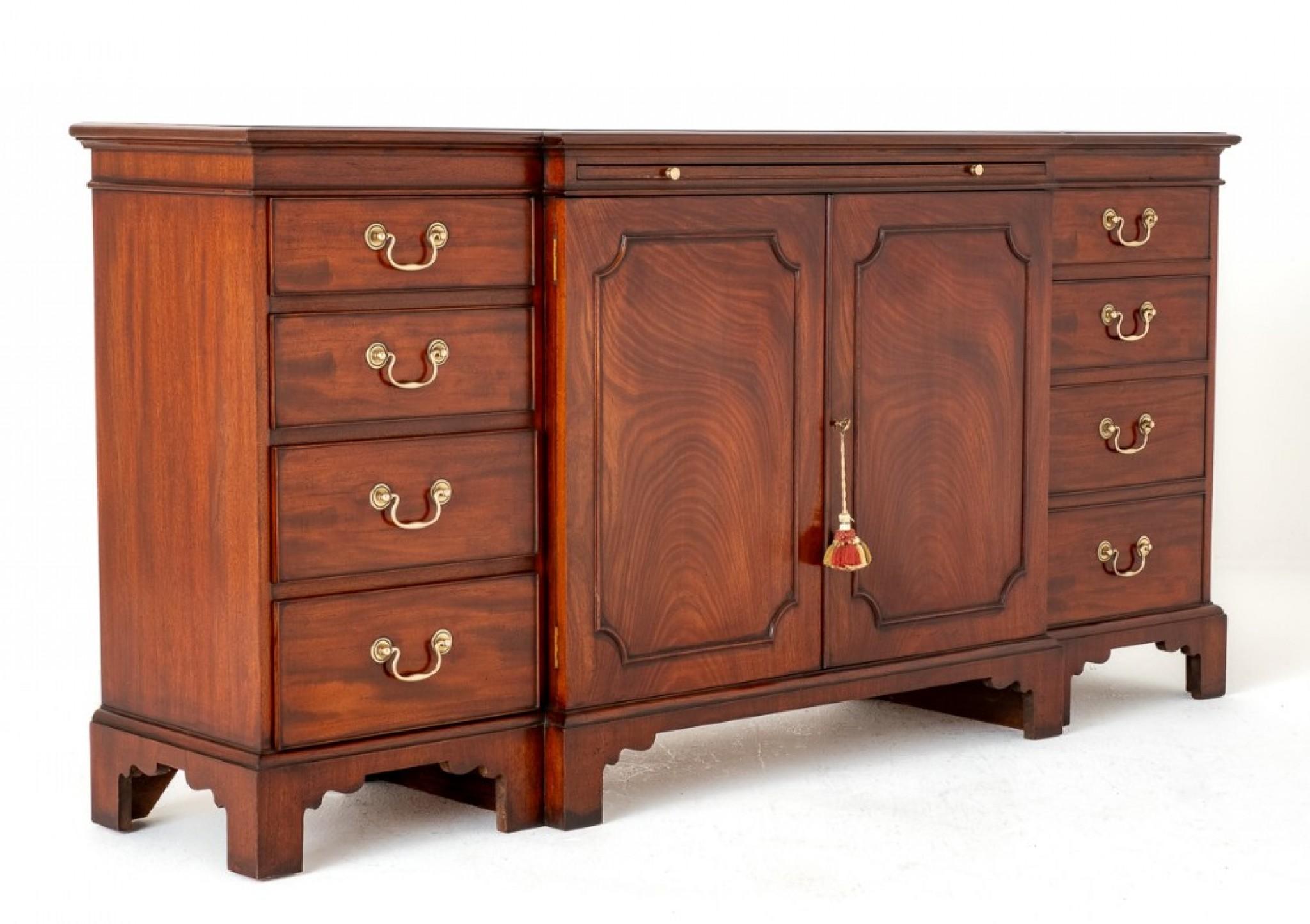 Georgian Revival Mahogany Breakfront Sideboard.
This Impressive Sideboard Stands upon Shaped Bracket Feet.
Having an arrangement of 7 Oak Lined Drawers and a Pullout Slide.
The Drawers Feature Brass Swan Neck Handles.
The Pair of Panelled Central